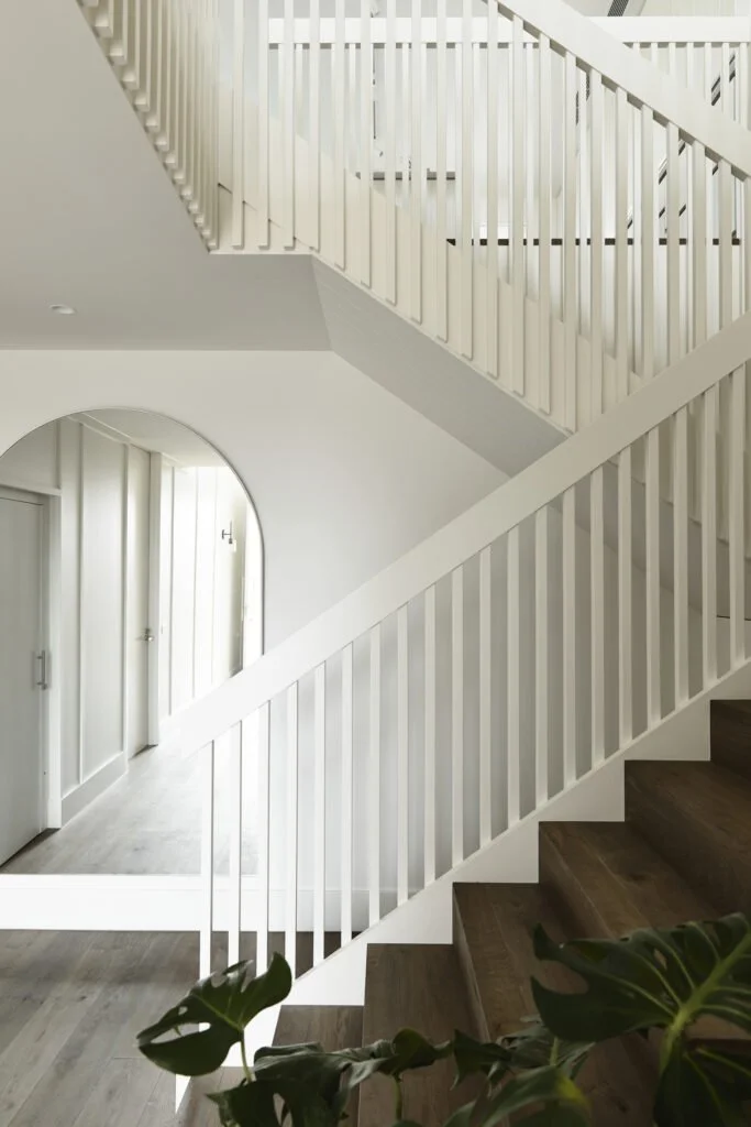 Interior of a modern home with a staircase and hallway with white walls and wood flooring.