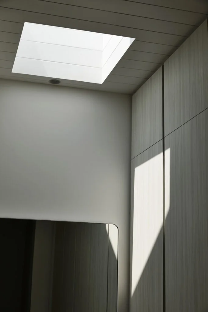 Interior room with a skylight window on the ceiling allowing sunlight to cast a shadow on the wall and built-in cabinetry.