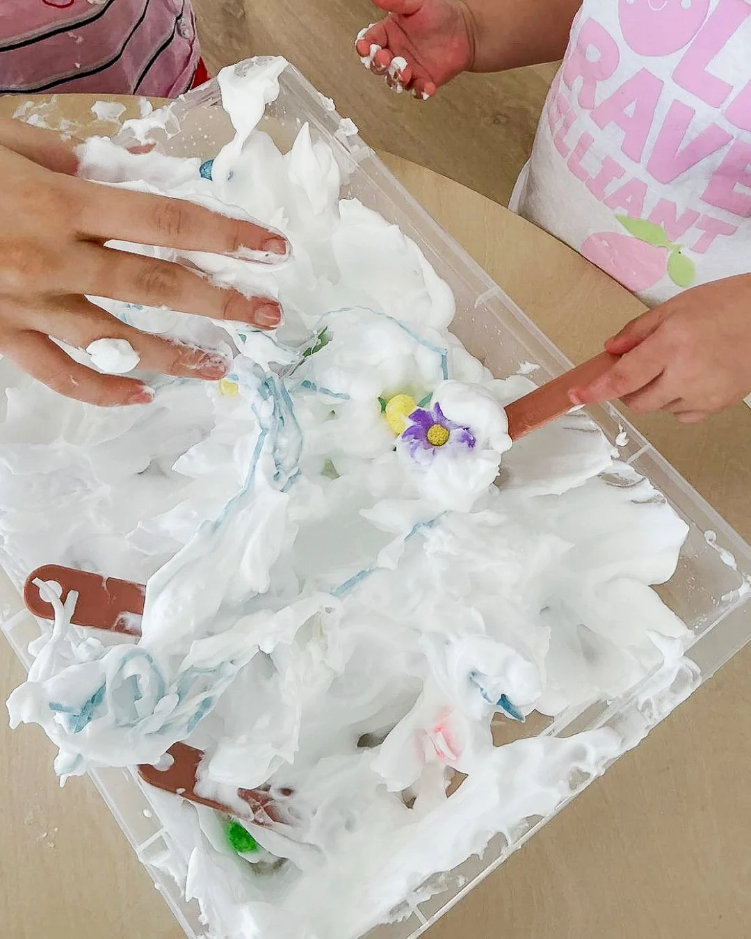👐 To a child, touch is the first language of discovery.

A tray filled with cloud-soft shaving cream, garden blooms, sticks and loose parts may look delightfully messy, but beneath the surface, it is a masterclass in early neurological development.
