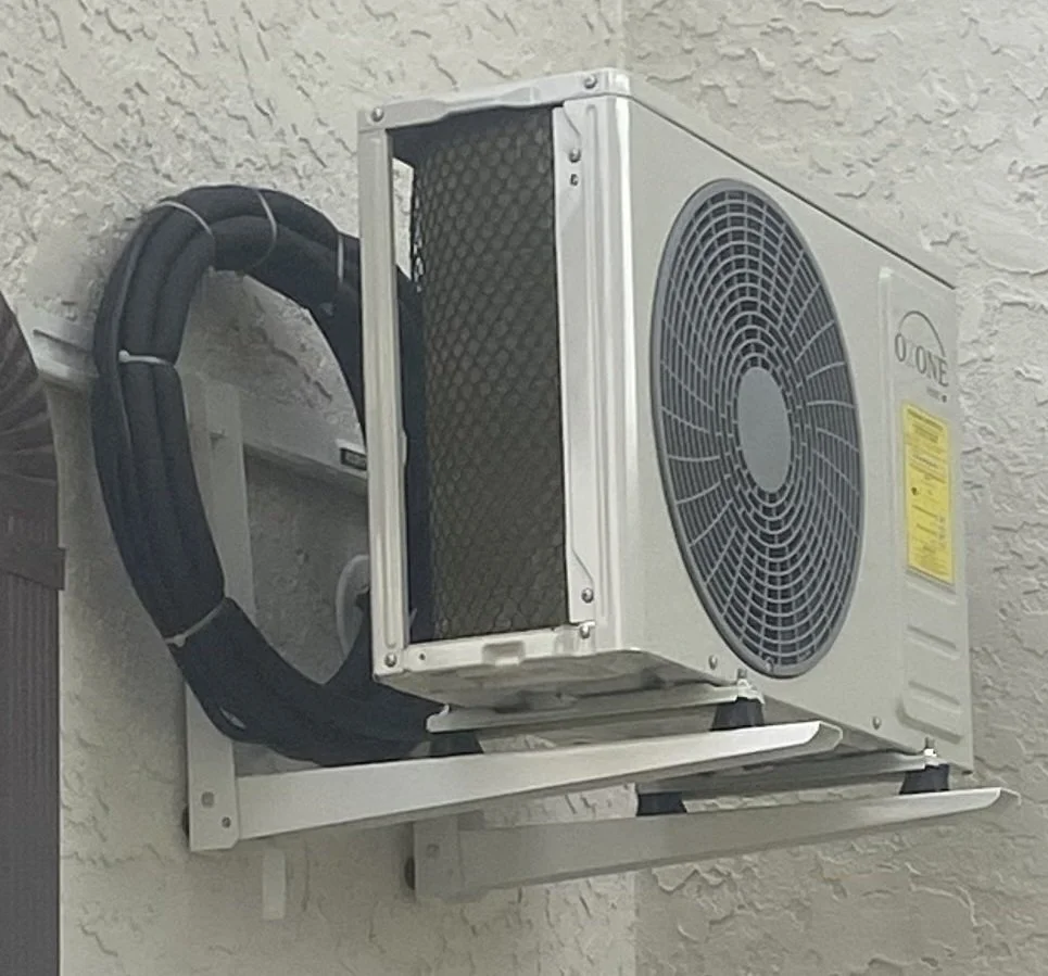 Outdoor HVAC system mounted on exterior wall, with large fan and insulated pipes.