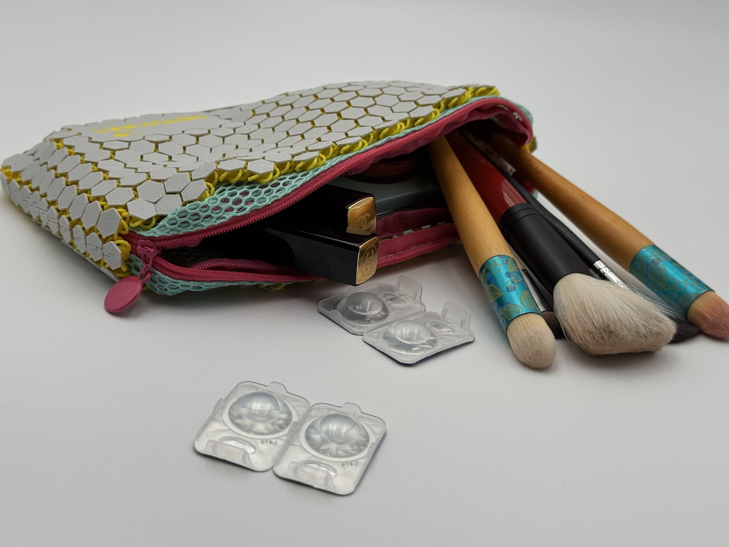 Perspective view of the ASTERYAM HexaFlux bag open, filled with makeup brushes and beauty essentials, highlighting the soft structure and wide zipper opening.