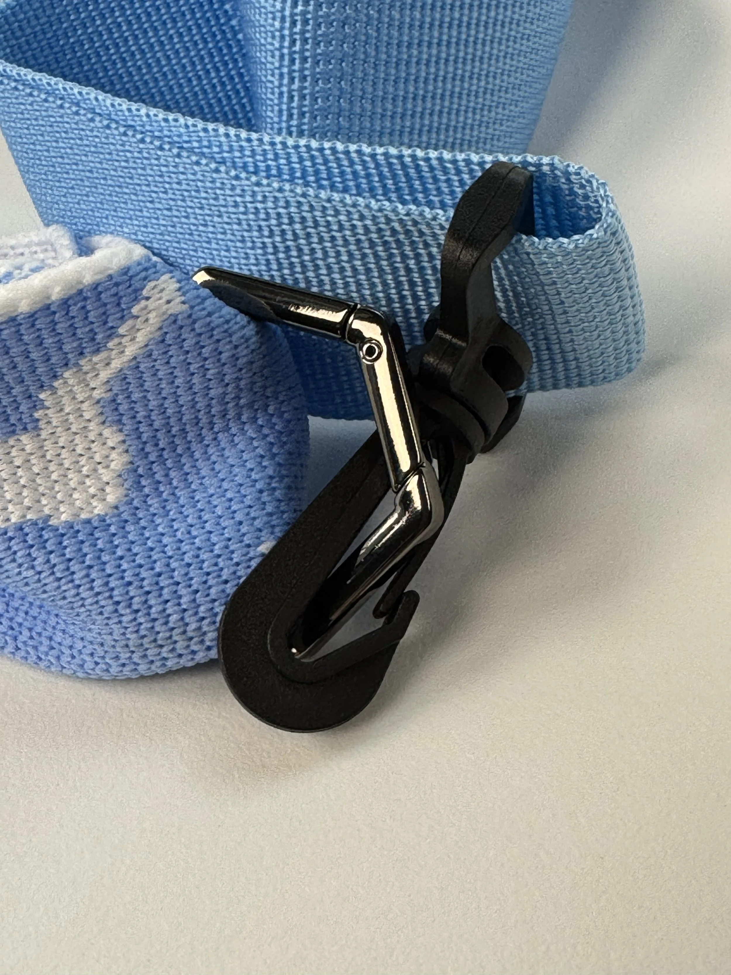 High-quality black and silver metal swivel clasp on a blue woven bag strap.