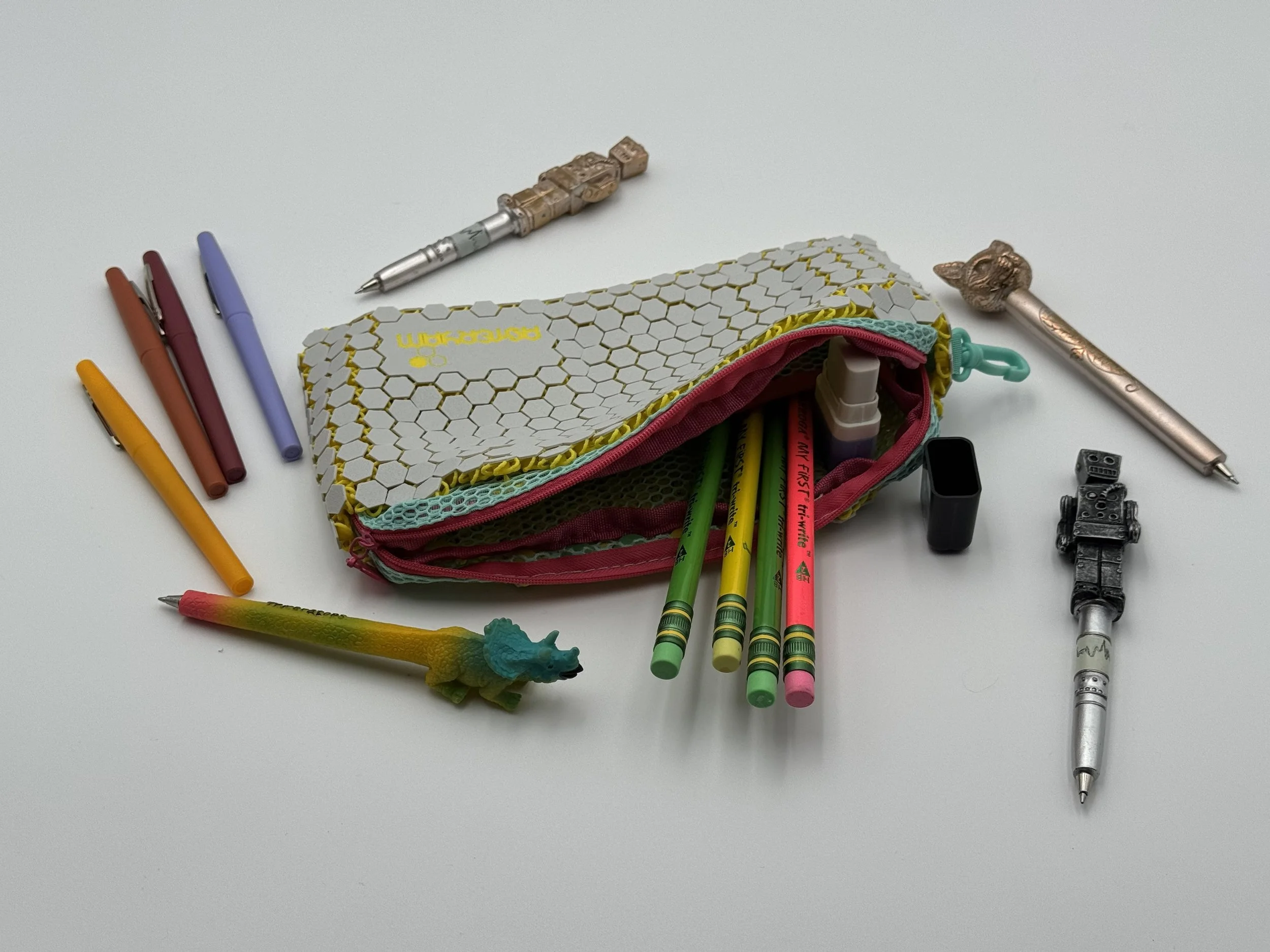 Open ASTERYAM HexaFlux bag with green and yellow pencils spilling out, demonstrating its capacity as a functional and stylish pencil holder.