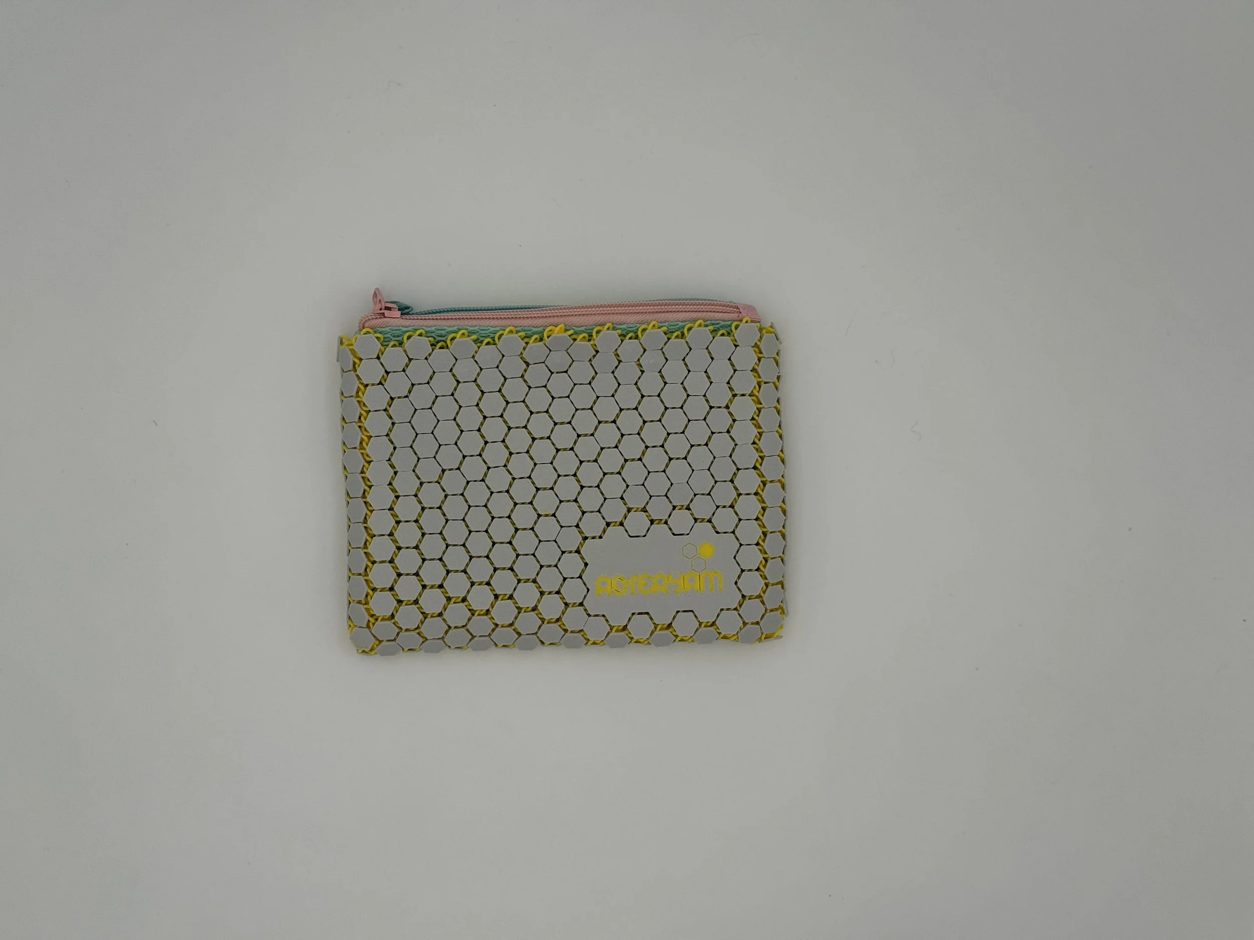 Front view of the ASTERYAM HexaDuo pouch featuring the signature light grey 3D printed hexagonal mesh shell, yellow inner accents, and the embossed ASTERYAM logo.