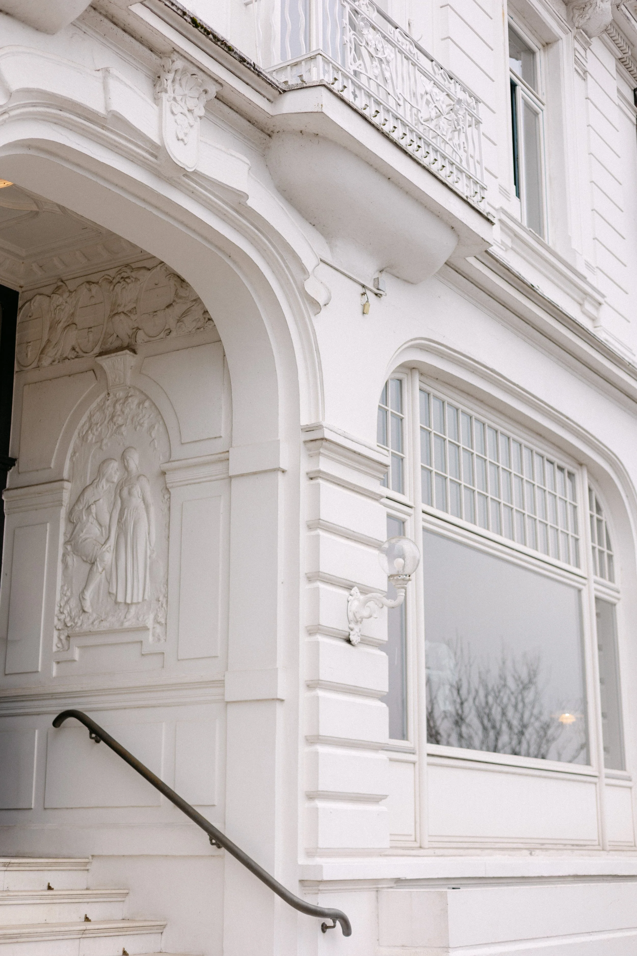 Ein weißes Gebäude mit barocker Architektur, Stuckverzierungen und einer Balustrade auf dem Balkon.