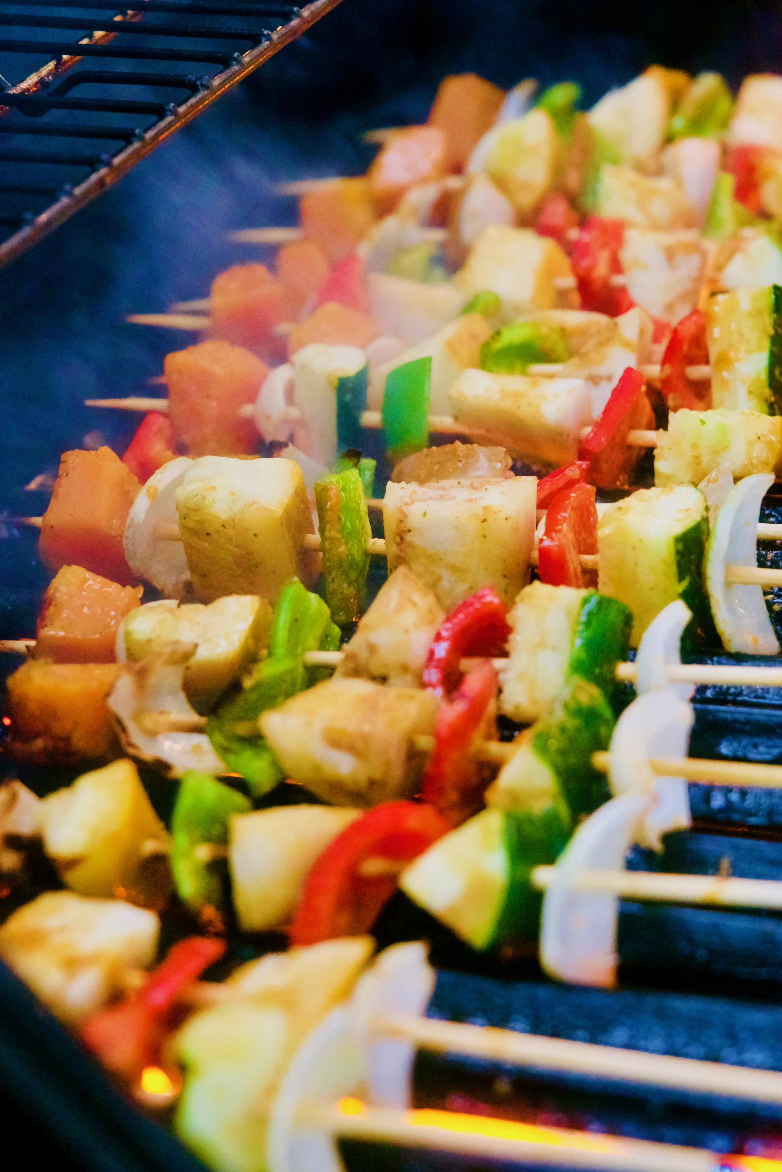 Brochetas de mariscos, verduras asadas con pimientos rojos, verdes, cebolla y champiñones sobre parrilla.