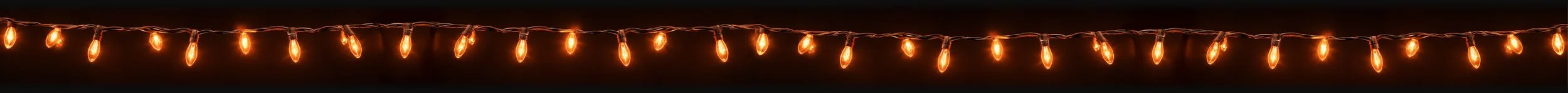 String of warm orange outdoor string lights hanging against a dark background.