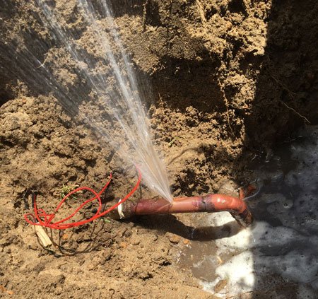 Water spraying out of burst underground pipe
