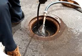 Jetter line spraying water down a blocked drain out of a hose