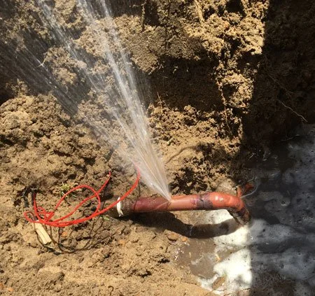 Dug up burst underground pipe spraying water