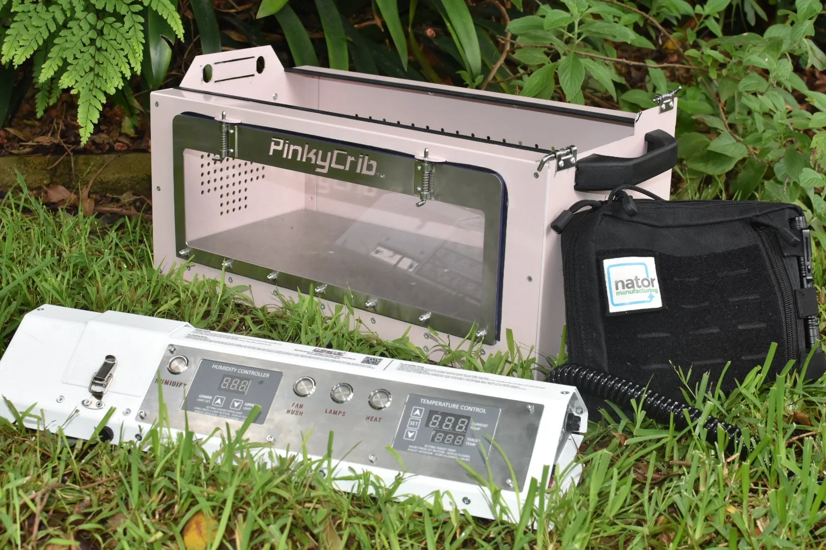A pink and white portable electronics enclosure for animals, resting on grass outdoors.