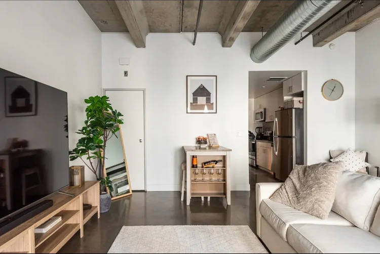 Casa Industrial — living area with TV console and kitchen beyond