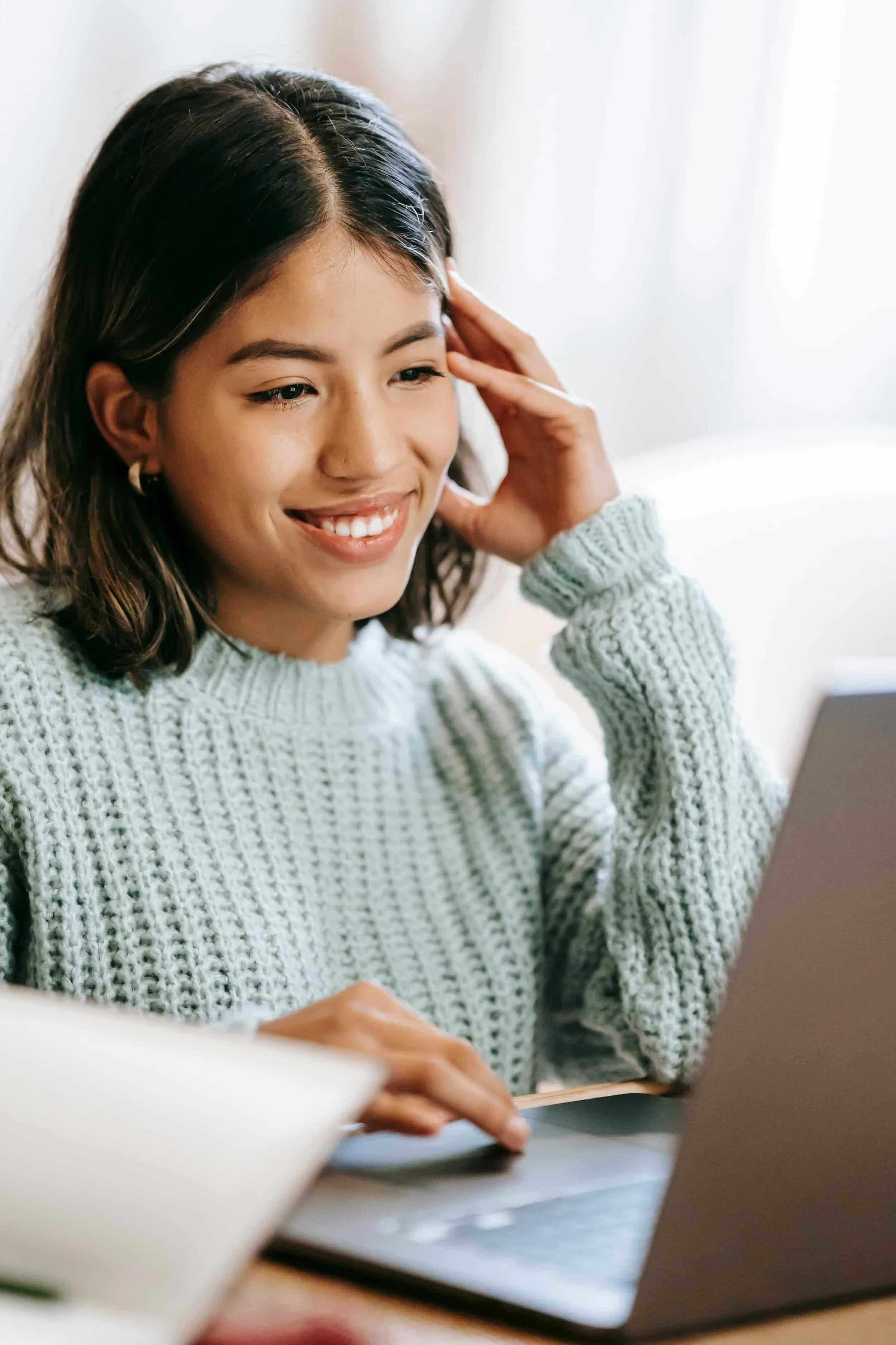Girl smiling at a computer screen doing anxiety therapy online.