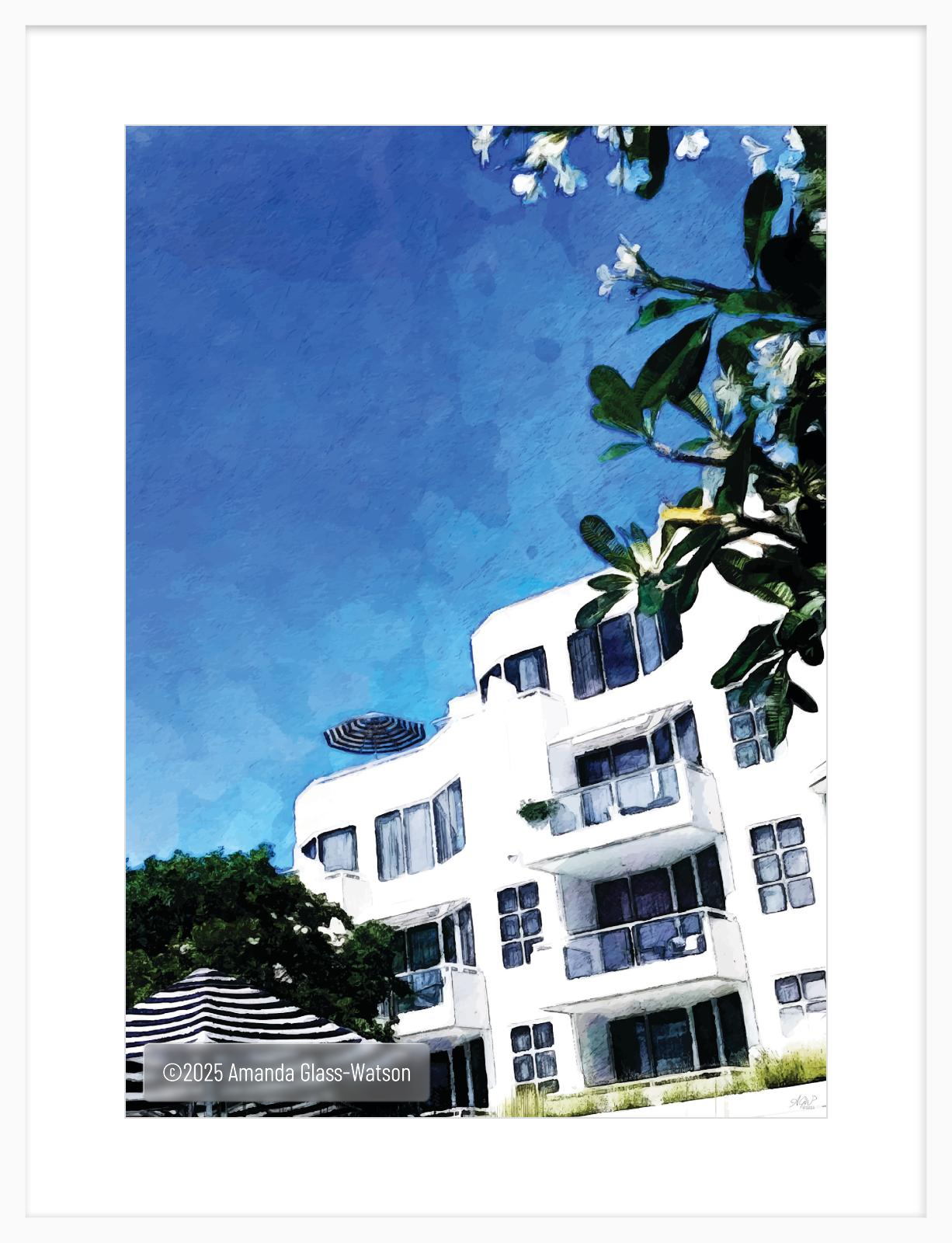 Elysium Afternoon framed print. Blue skies, white hotel, frangipani trees and umbrellas