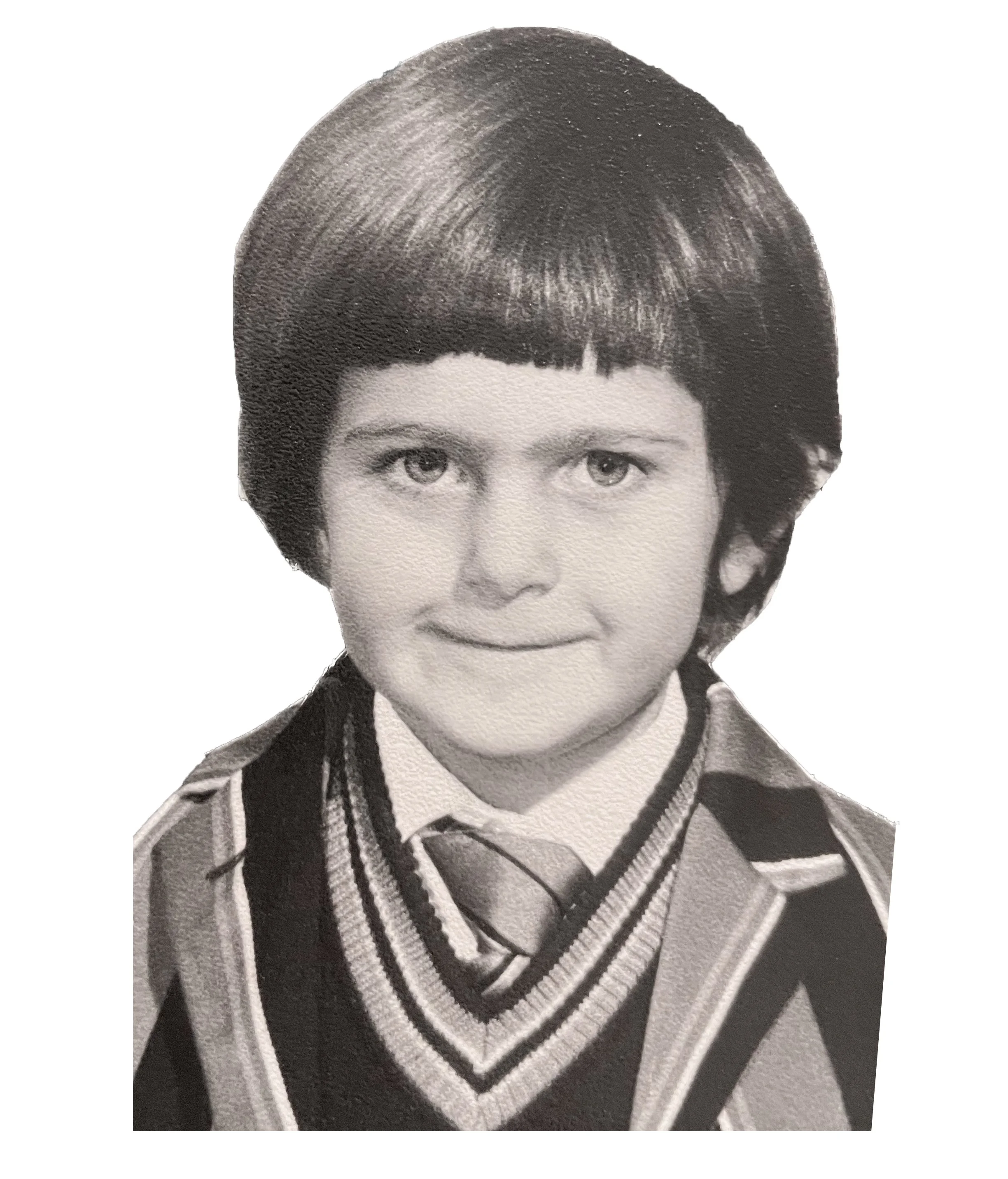 Child with short dark hair wearing a school uniform with a striped tie and sweater vest, smiling at the camera in black and white.
