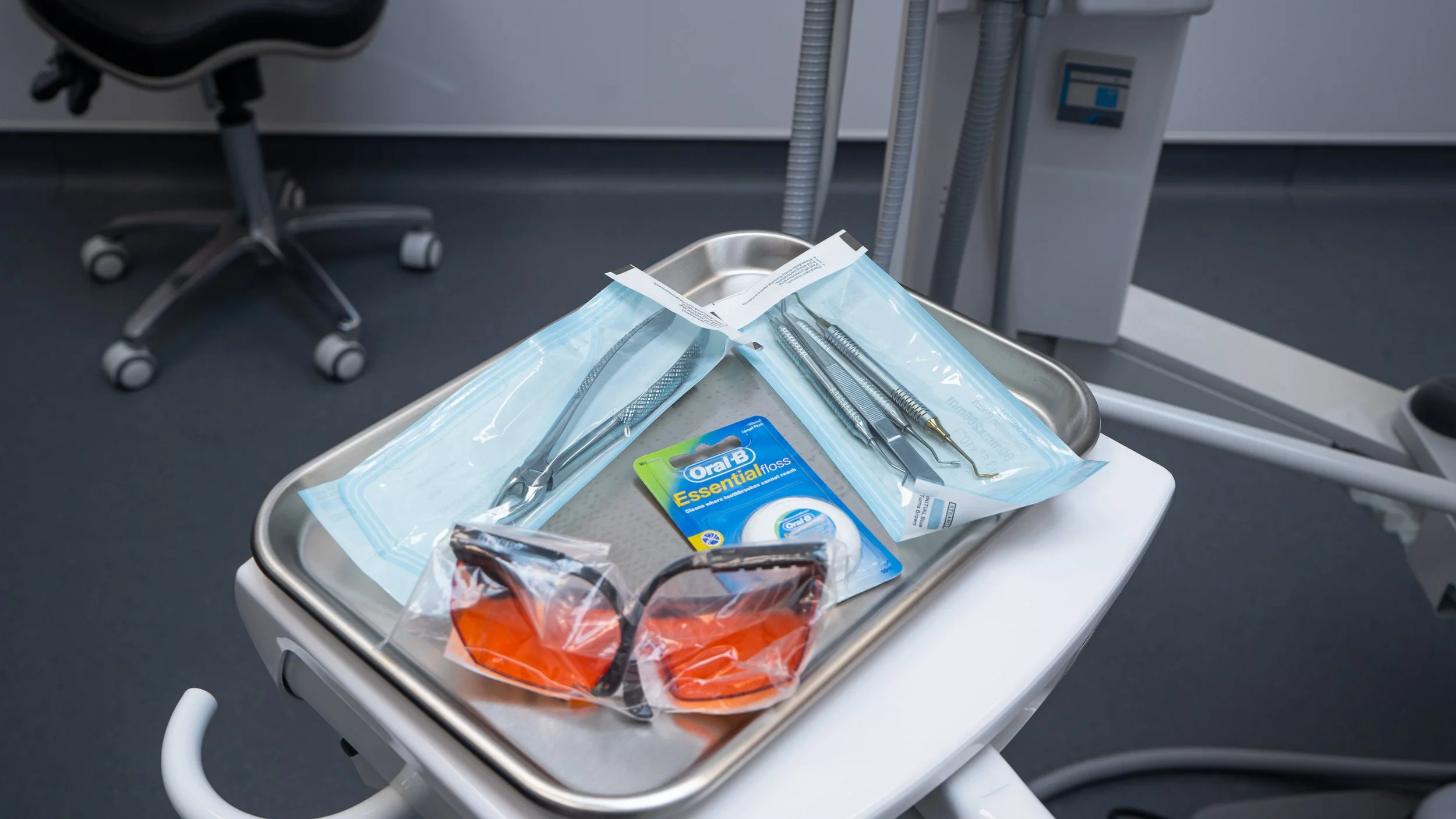 A person wearing blue gloves organizing medical or surgical instruments on a white tray.