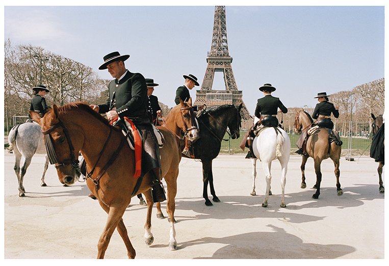 A group of people riding horses with the Eiffel Tower in the background.