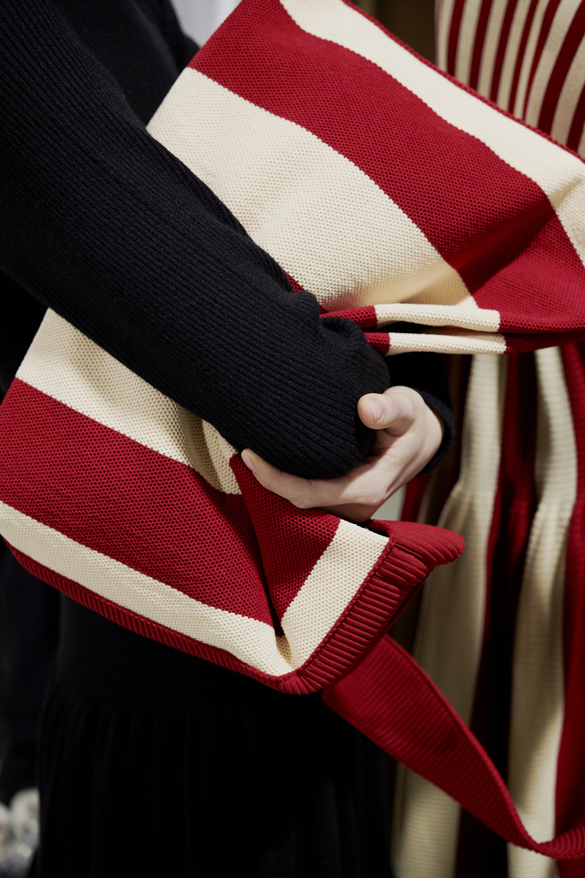 Person holding a bag with red and white striped pattern.