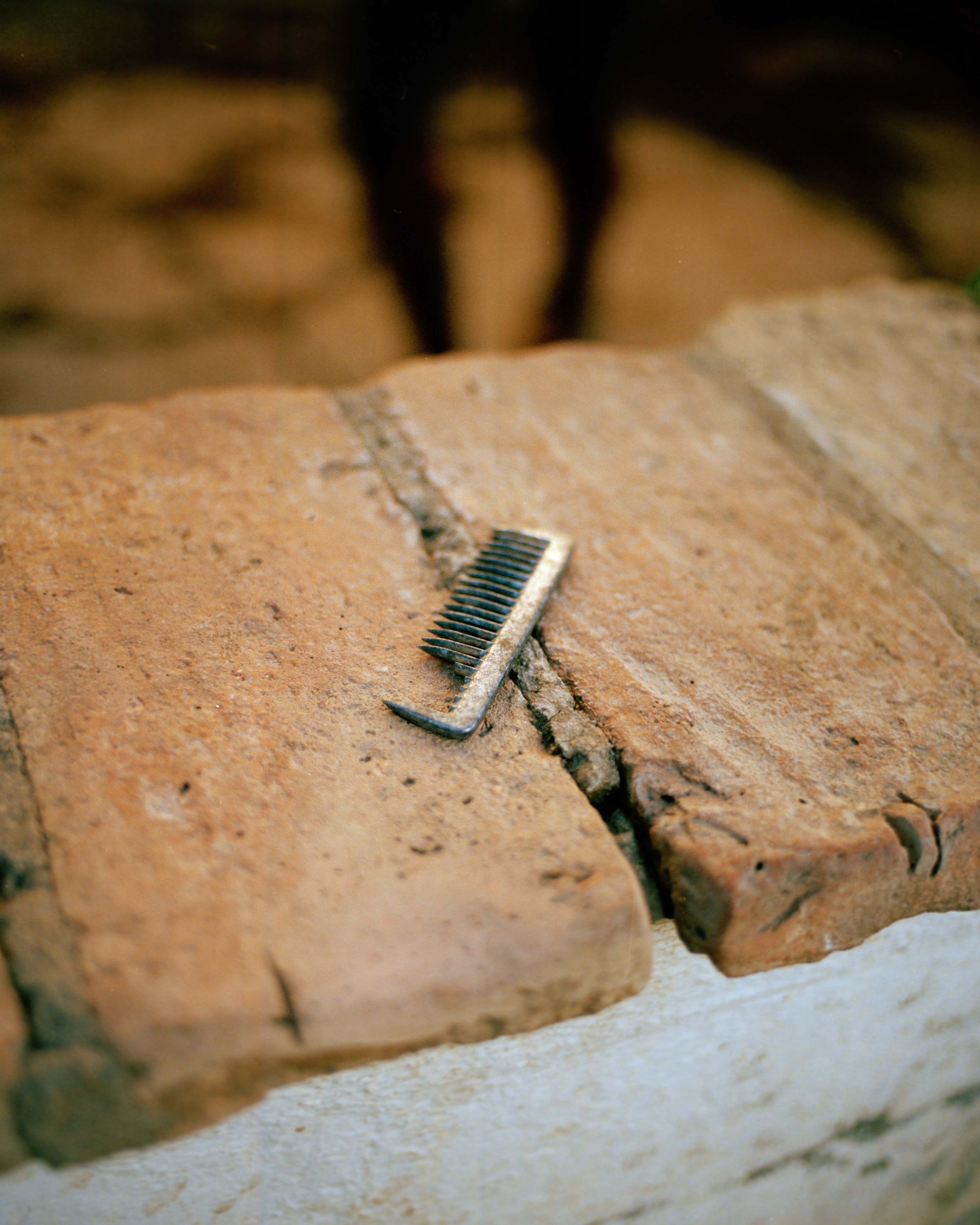A straight razor rest on a brick wall, with a blurred background.