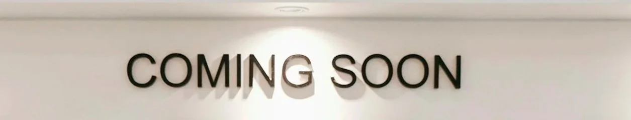 Ein Schild mit der Aufschrift "COMING SOON" in schwarzen Buchstaben auf weißem Hintergrund.