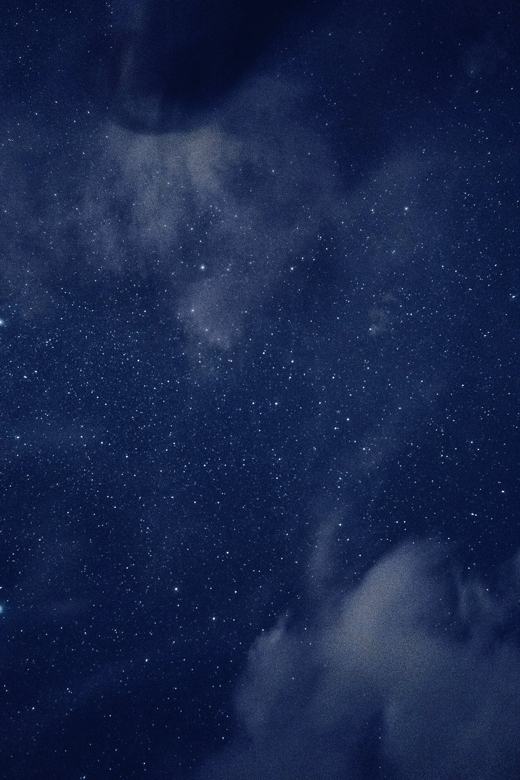 Night sky filled with numerous stars and some clouds.