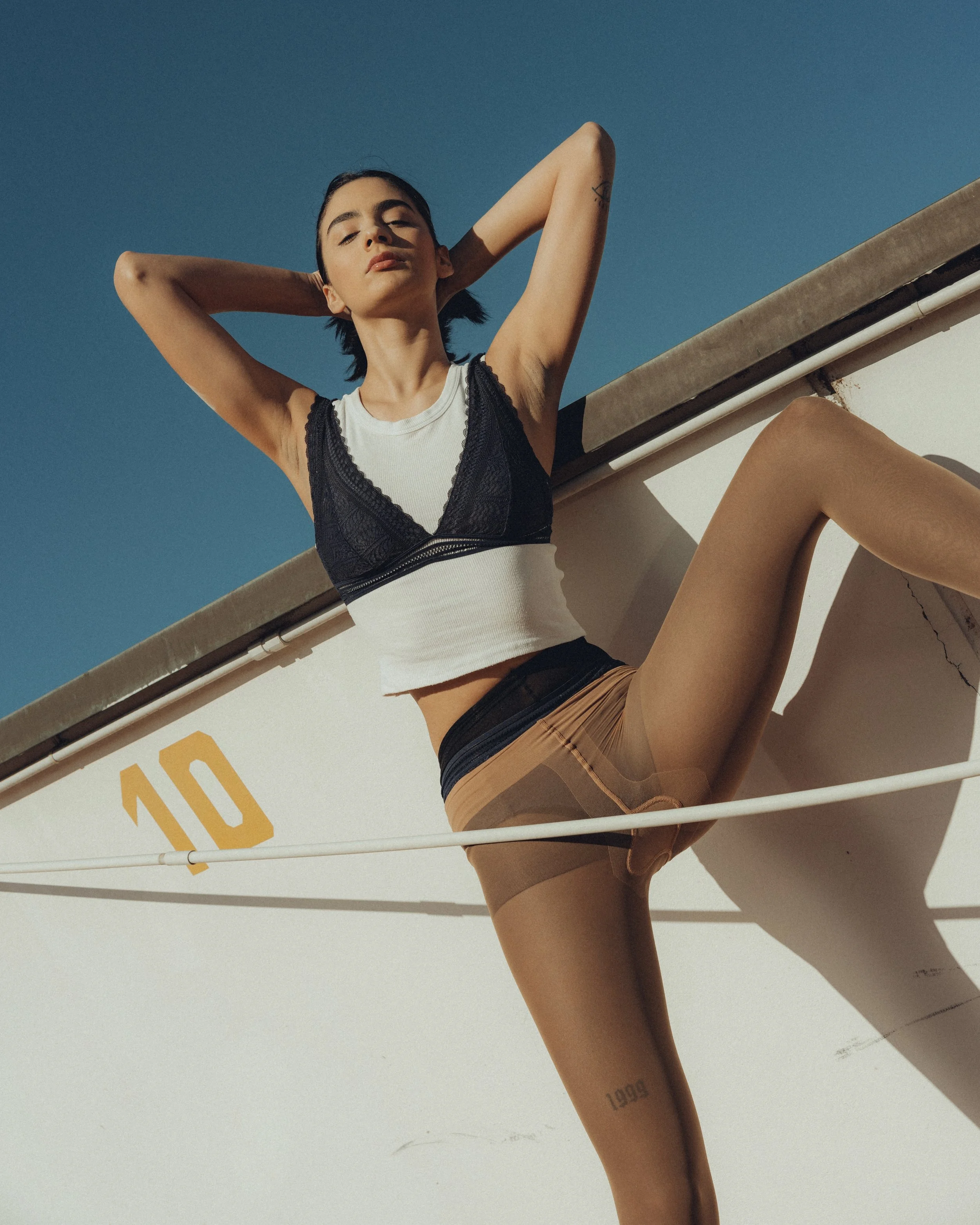 Cinematic lifestyle fashion model  woman rooftop arms behind head clear blue sky Milan — Nicco Mandelli