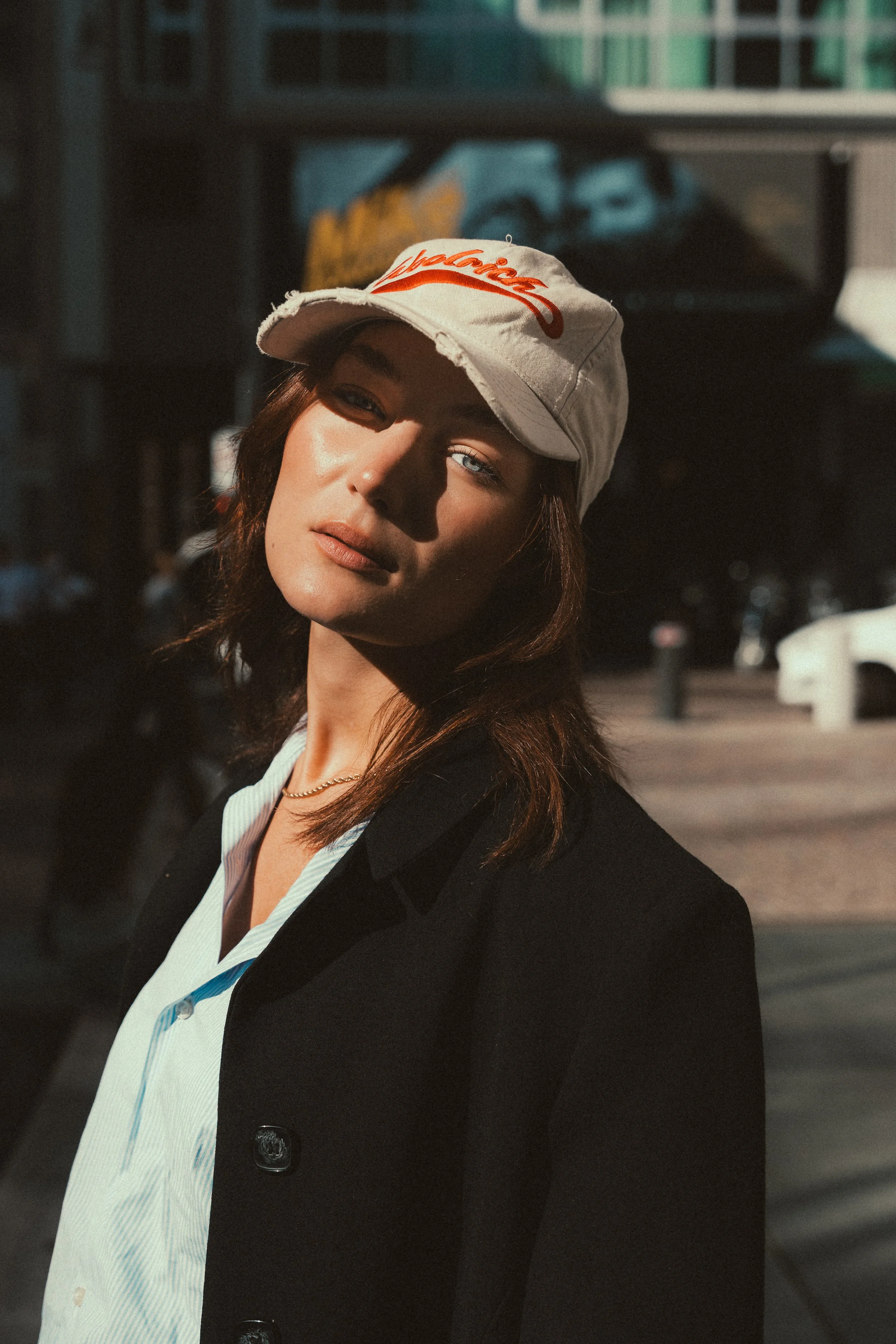 Street fashion portrait woman baseball cap striped shirt black blazer outdoor Milan