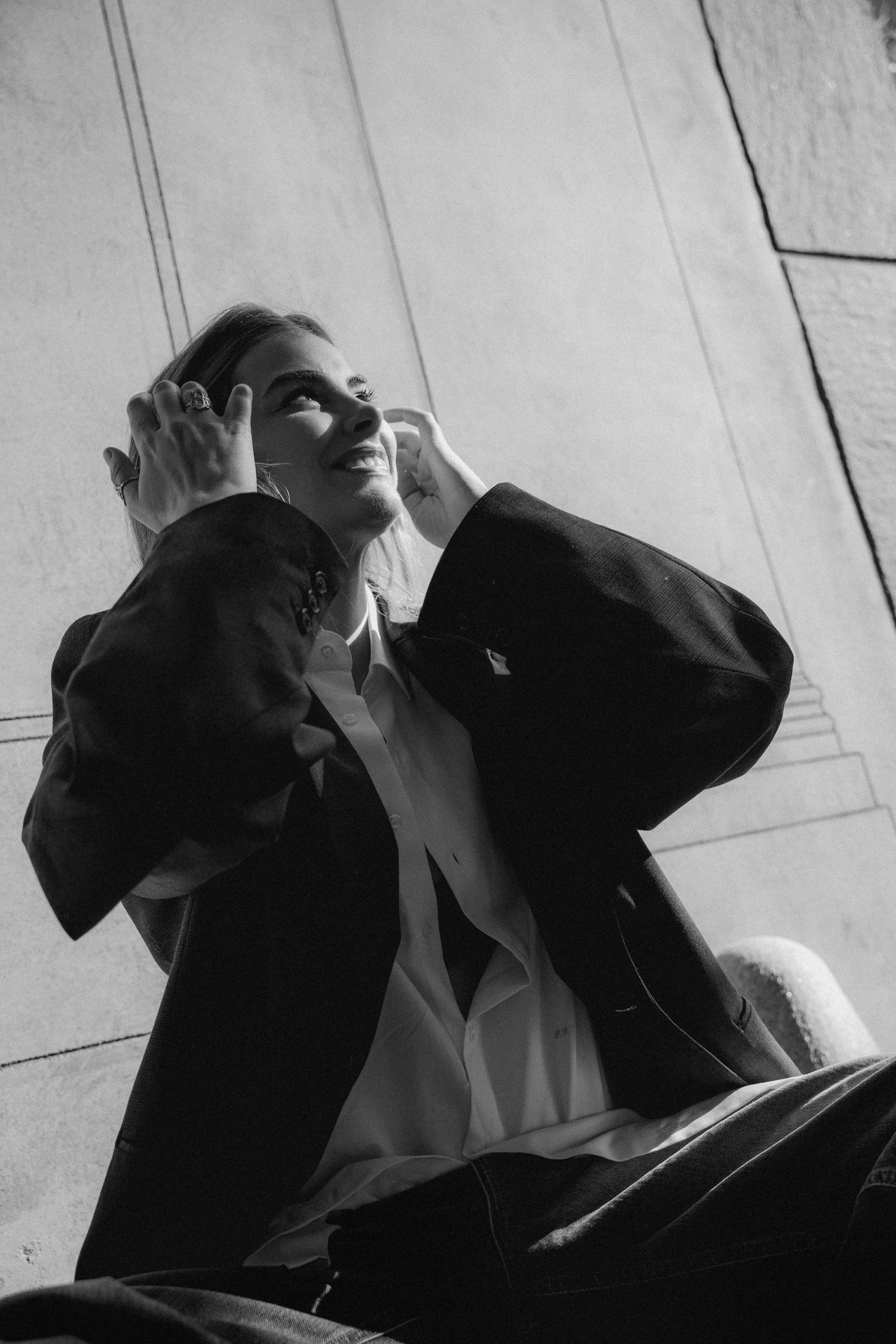 Lifestyle fashion portrait woman dark blazer white shirt sitting Milan sidewalk — Nicco Mandelli