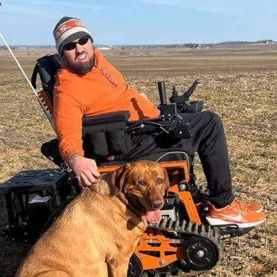 Travis and his best friend Ruby Hope riding through the fields in his new track chair from his FarmTok Family.