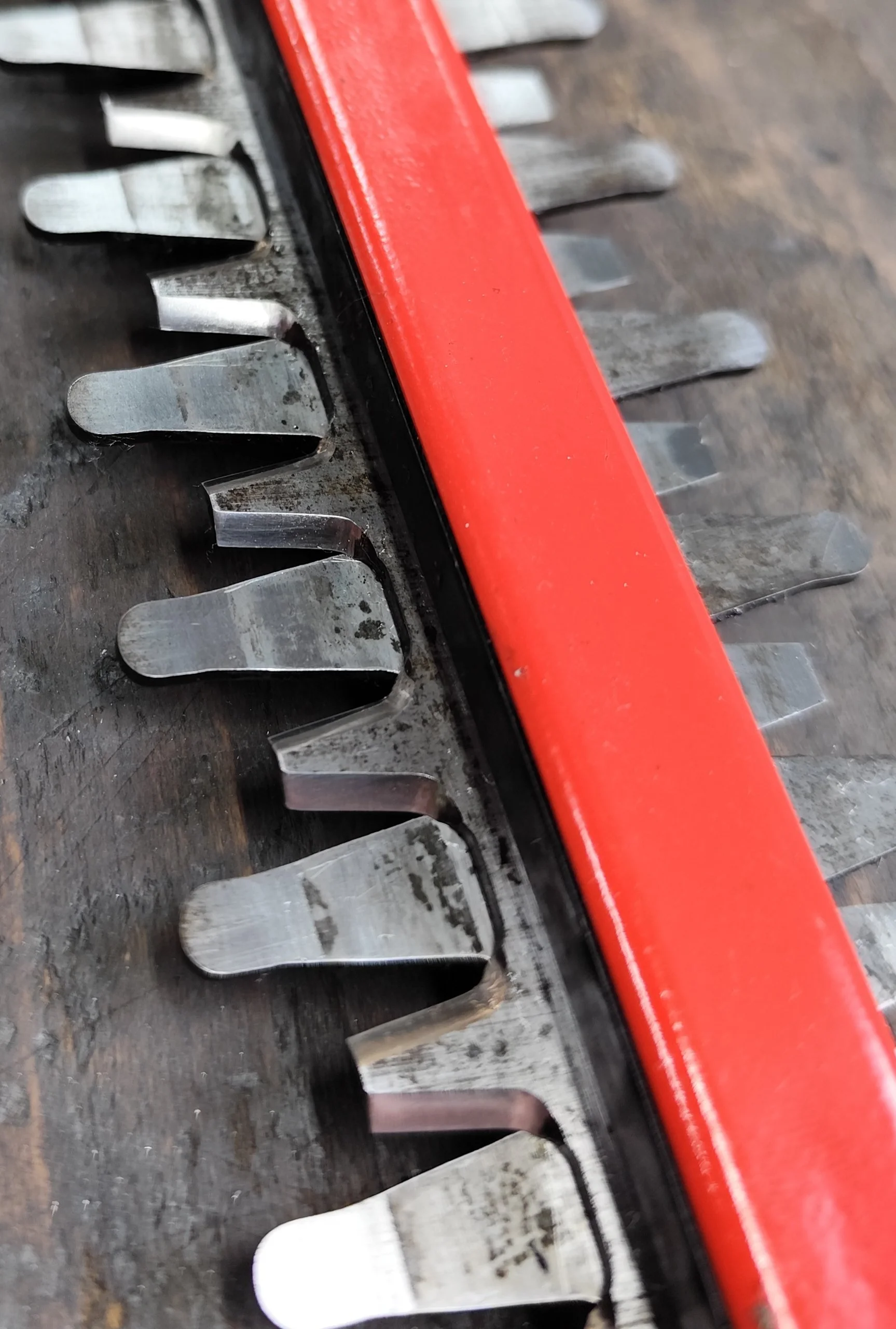 Nahaufnahme eines Rasenmähermessers mit roten Schutzabdeckung auf einer Werkbank.