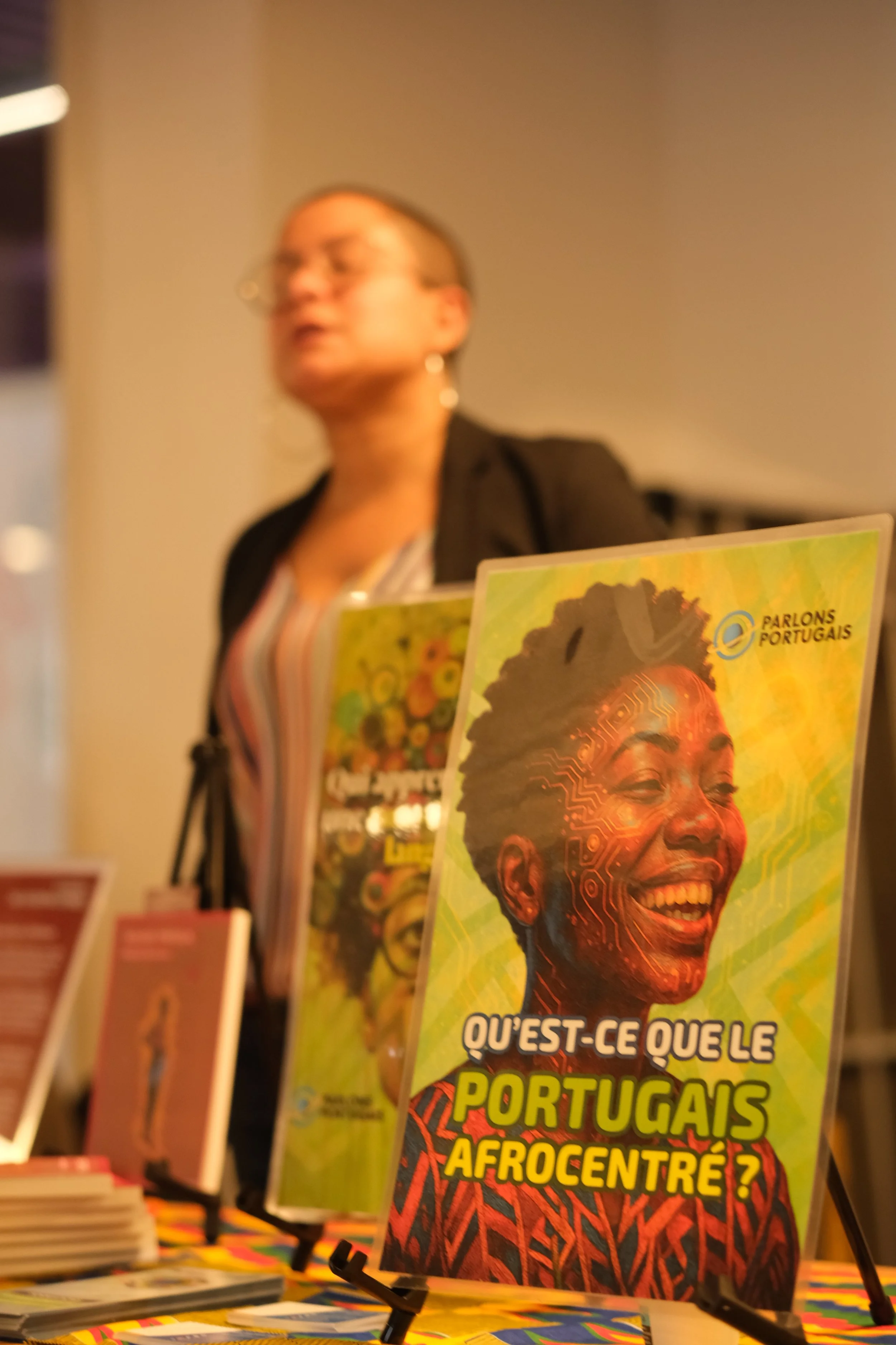 Couverture d'un magazine avec un portrait d'une femme afro-portugaise souriante, avec un fond coloré et le texte 'Qu'est-ce que le Portugais Afrocentré ?'