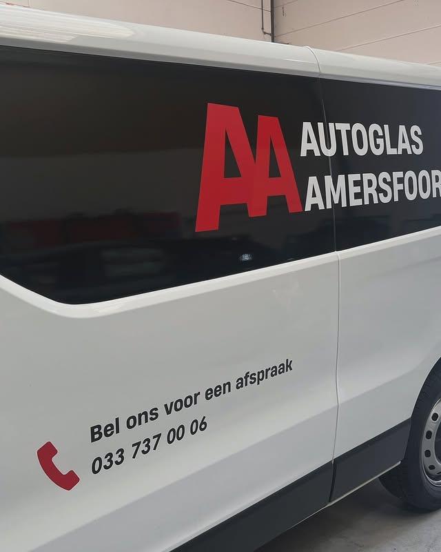 Side of a white vehicle with the logo and contact information for Autoglas Amersfoort, a vehicle glass repair service. The logo features red and white letters and the text is in Dutch, including a phone number and a message to call for an appointment.