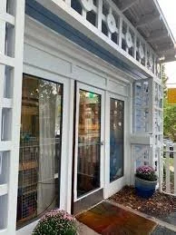 Storefront with glass door and window, decorated with flower pots outside.
