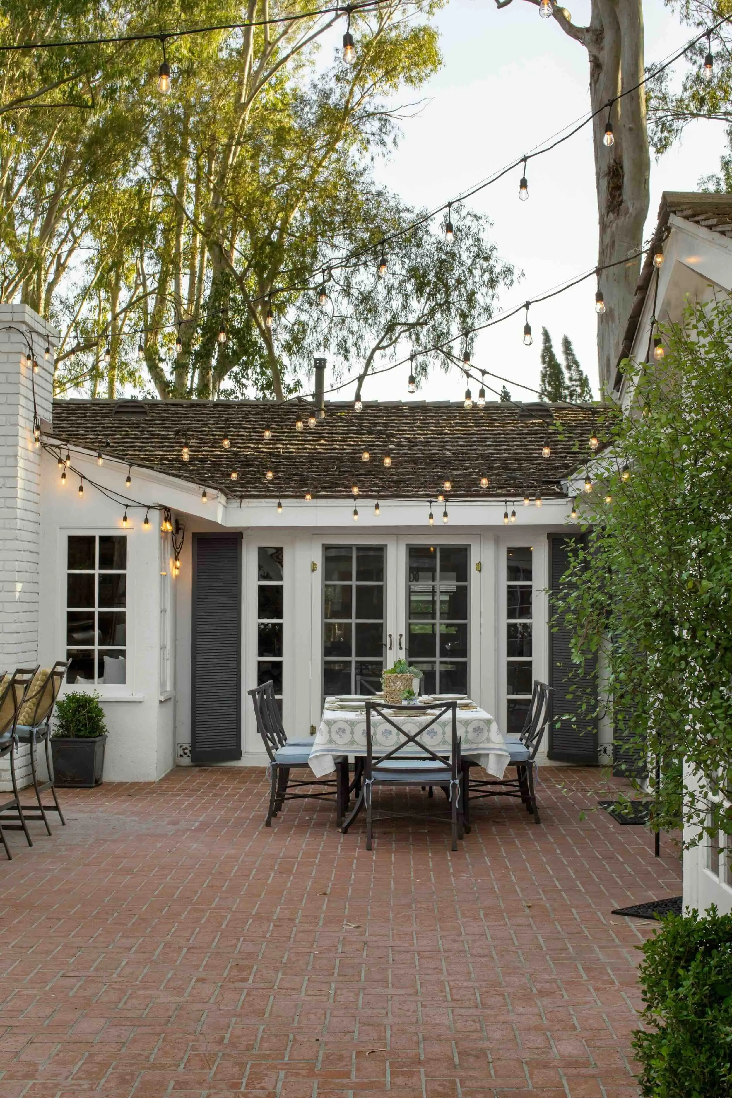Outdoor dining area beneath string lights in a Palos Verdes Estates home, designed by Julie Beuerlein
