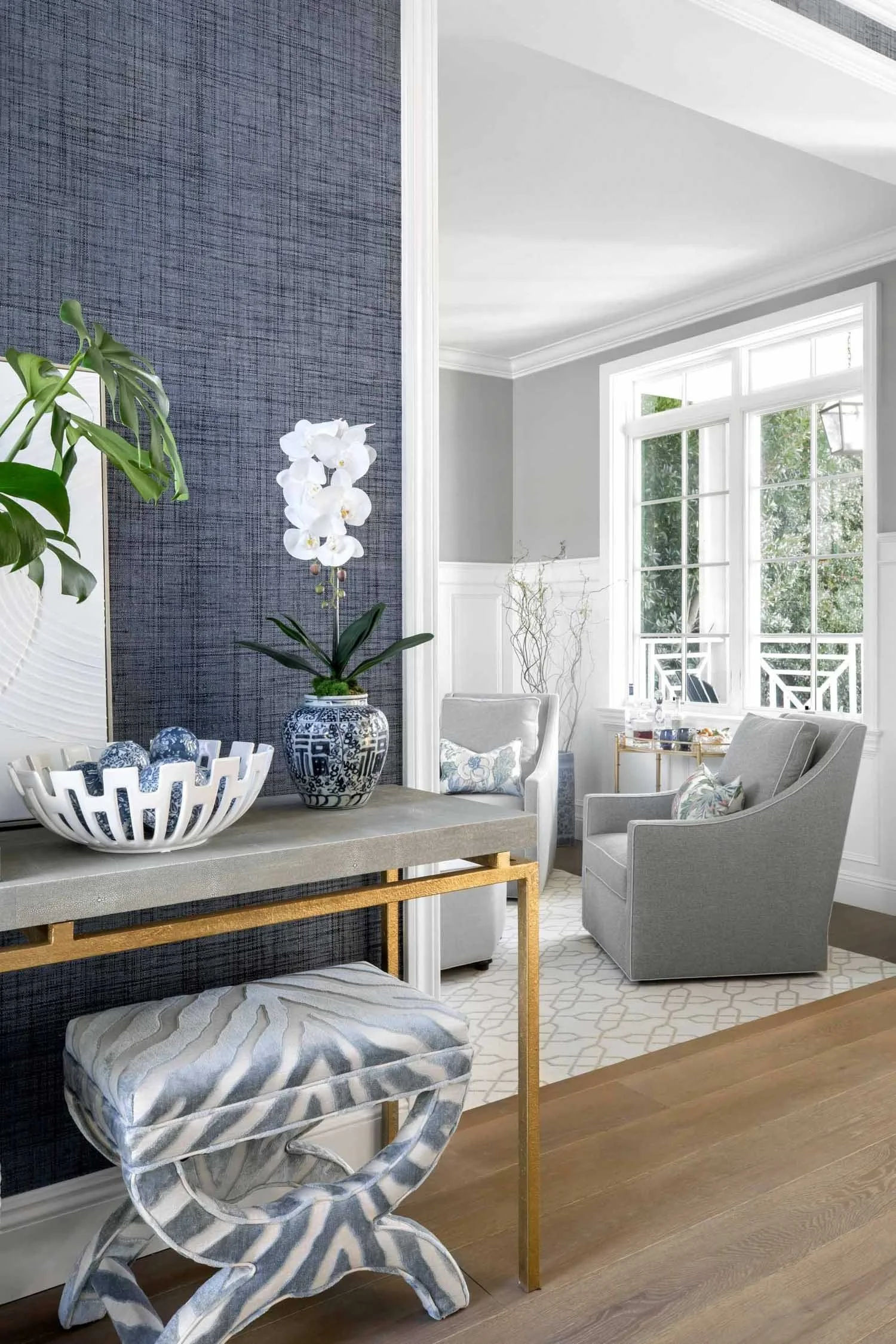 Sophisticated blue wallpapered entry with stone table, designed by JKB Home Design, Southern California