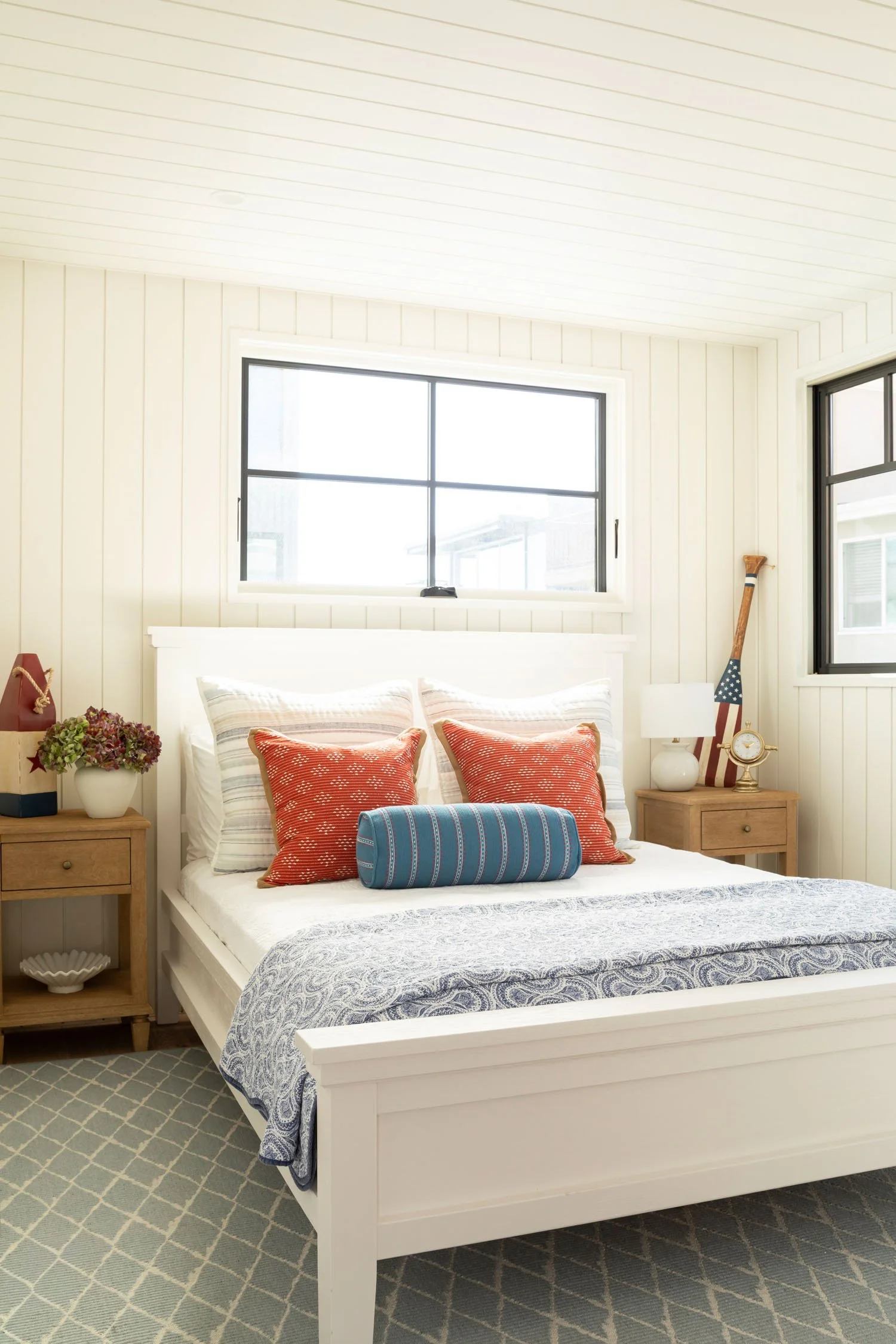 Coastal bedroom with white paneled walls and colorful layered bedding in Manhattan Beach, designed by Julie Beuerlein
