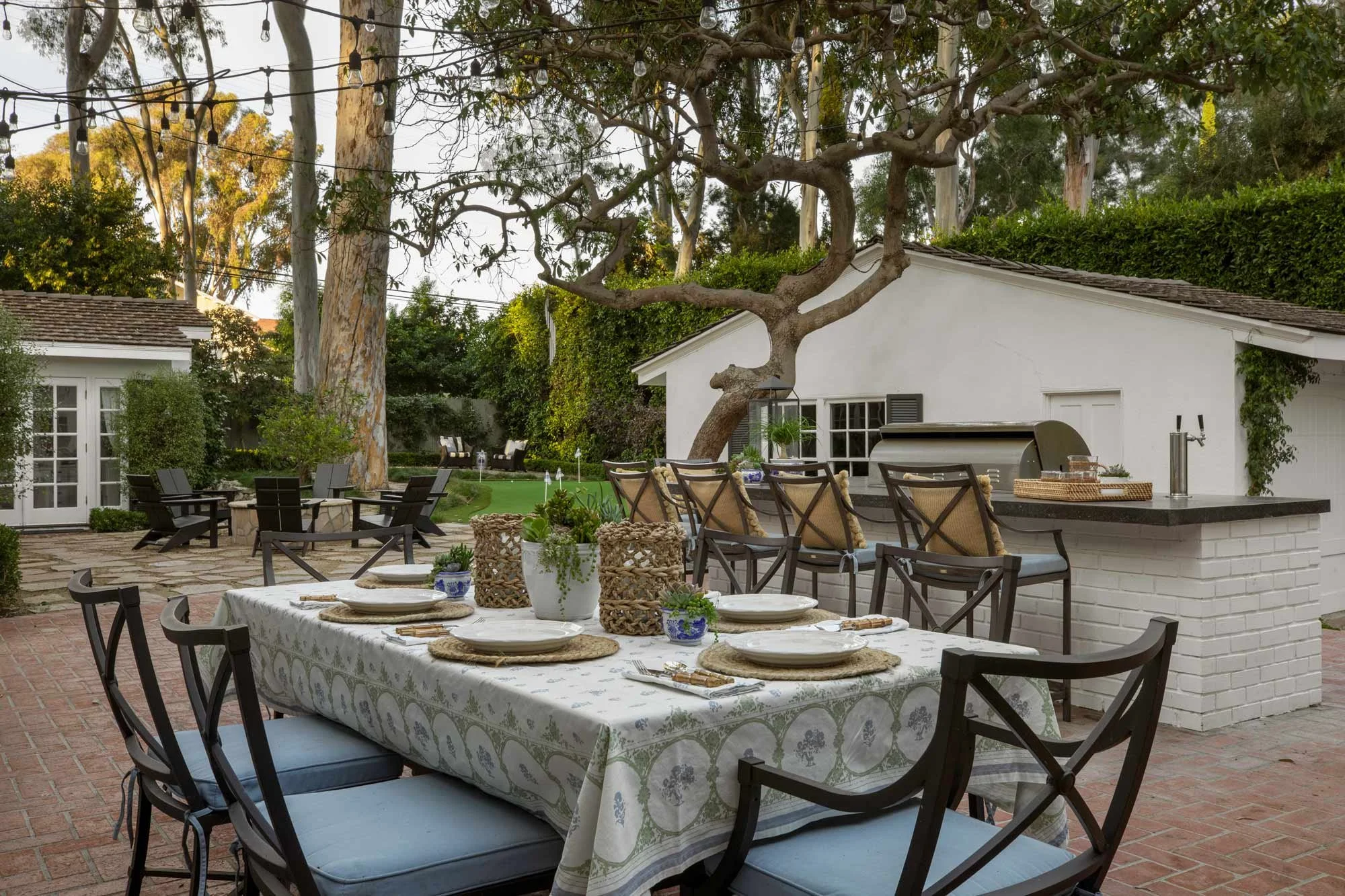 Outdoor dining and kitchen area with bistro lights in Palos Verdes ranch, designed by JKB Home Design