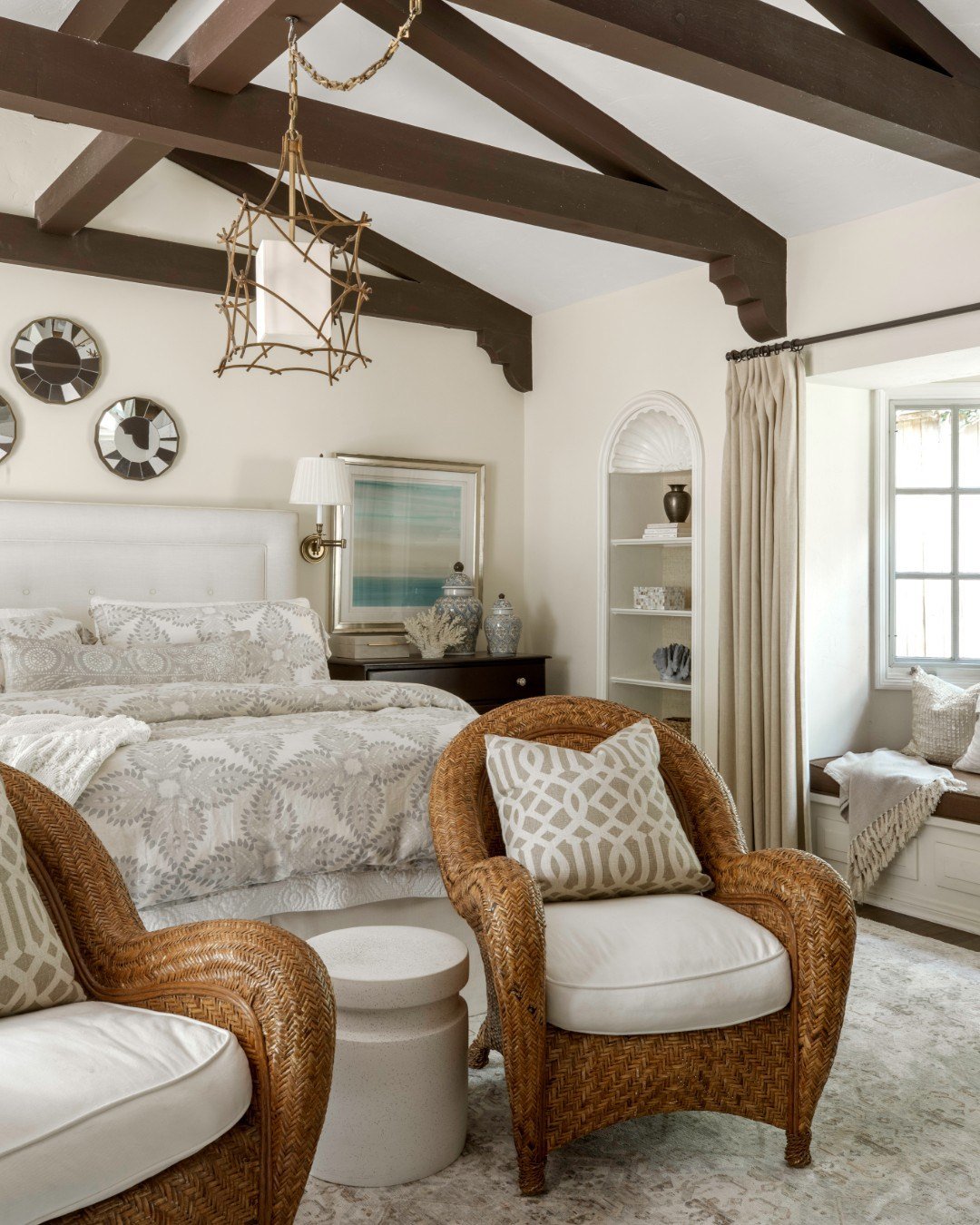 This Ranch Revival primary bedroom remains one of my favorite spaces to date. The exposed beams bring quiet structure, the hanging chandelier adds a soft sense of drama, and the statement chairs create an inviting moment to pause. Layered with a fire