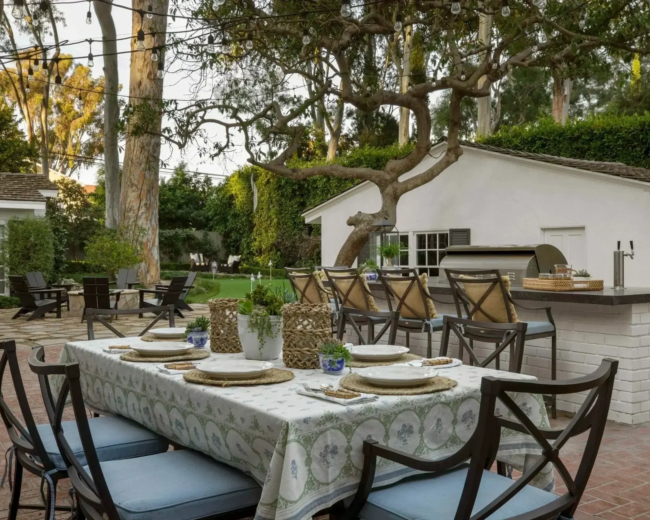 Outdoor dining and kitchen area with bistro lights in Palos Verdes ranch, designed by JKB Home Design