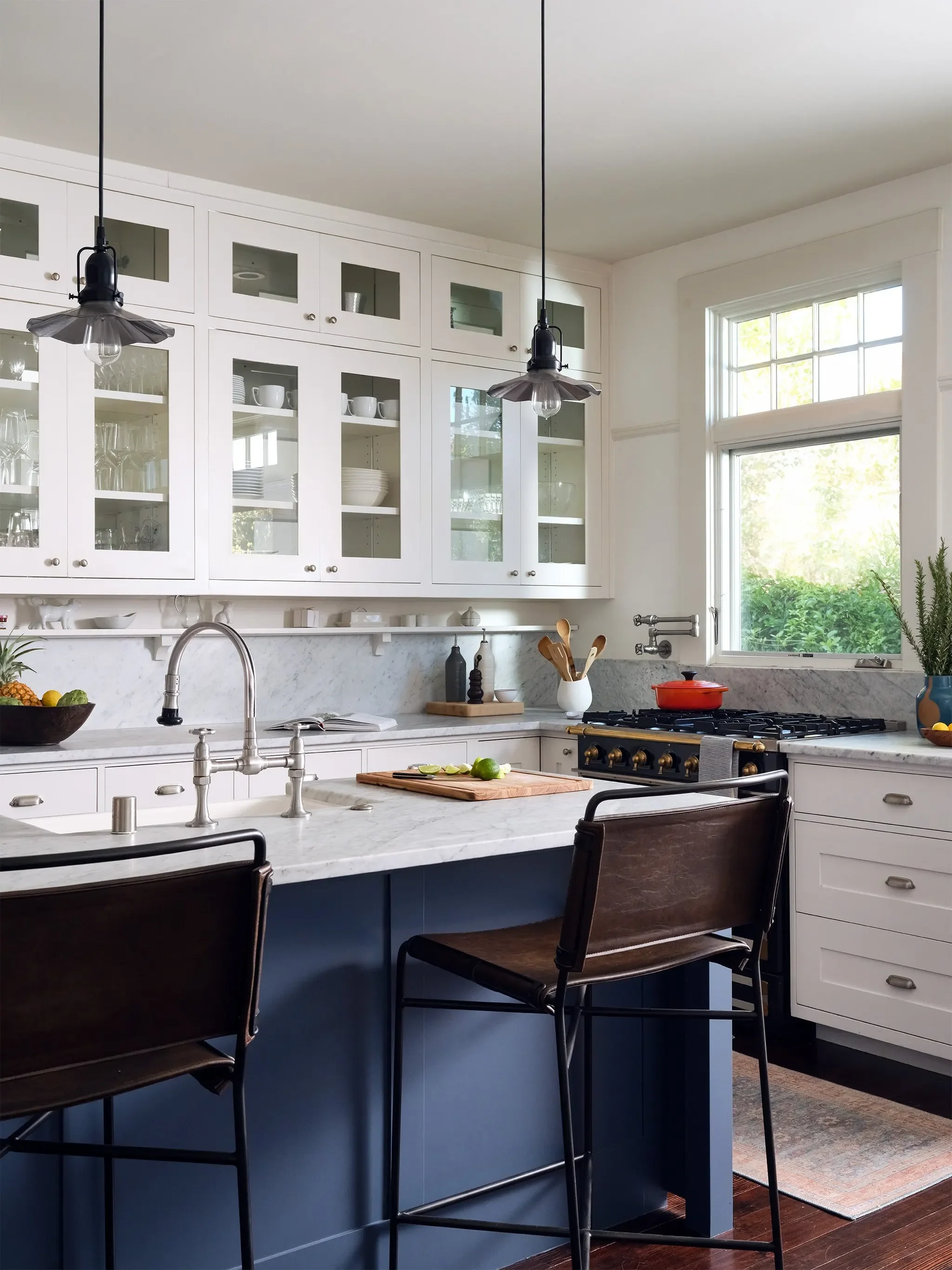 San Anselmo kitchen with white cabinetry, marble counters, blue island, and leather counter stools by JKB Home Design