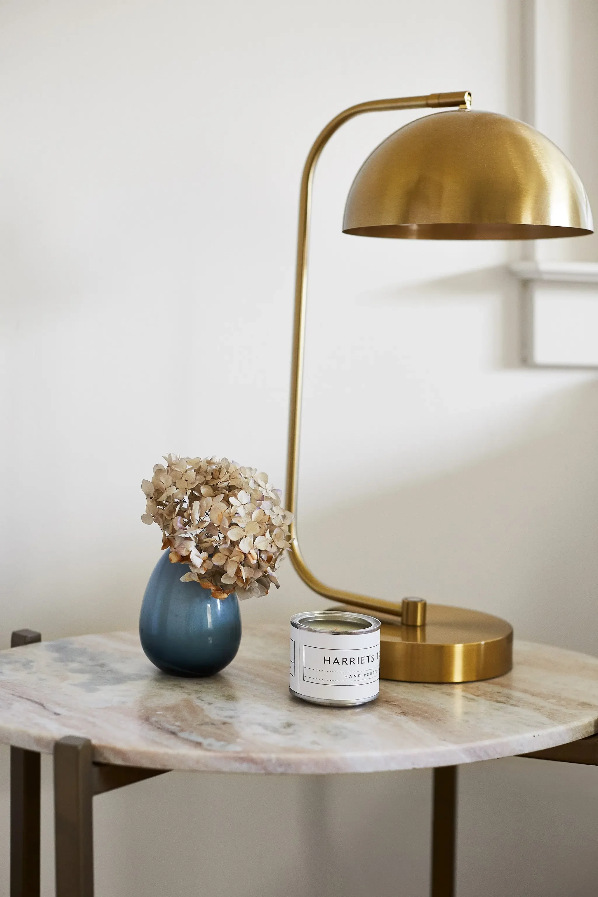 Styled marble side table with brass lamp, blue vase, and decorative candle in a San Anselmo home by JKB Home Design