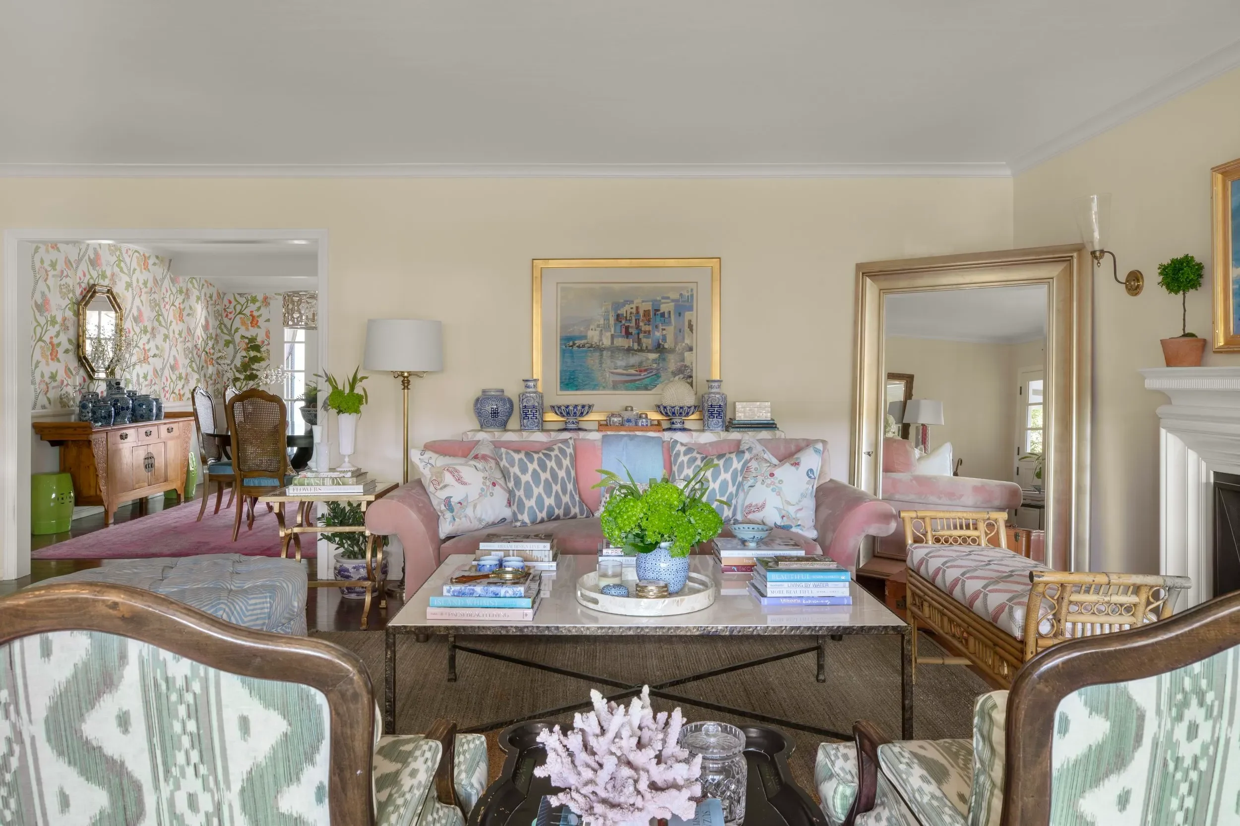 Traditional living room with pink sofa, patterned armchairs, vintage-inspired furniture, and collected decor by JKB Home Design