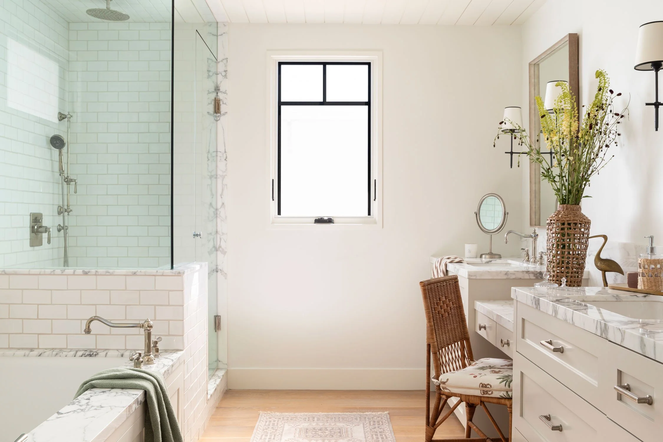 Bright primary bathroom with marble vanity, soaking tub, and glass shower in Manhattan Beach, designed by JKB Home Design