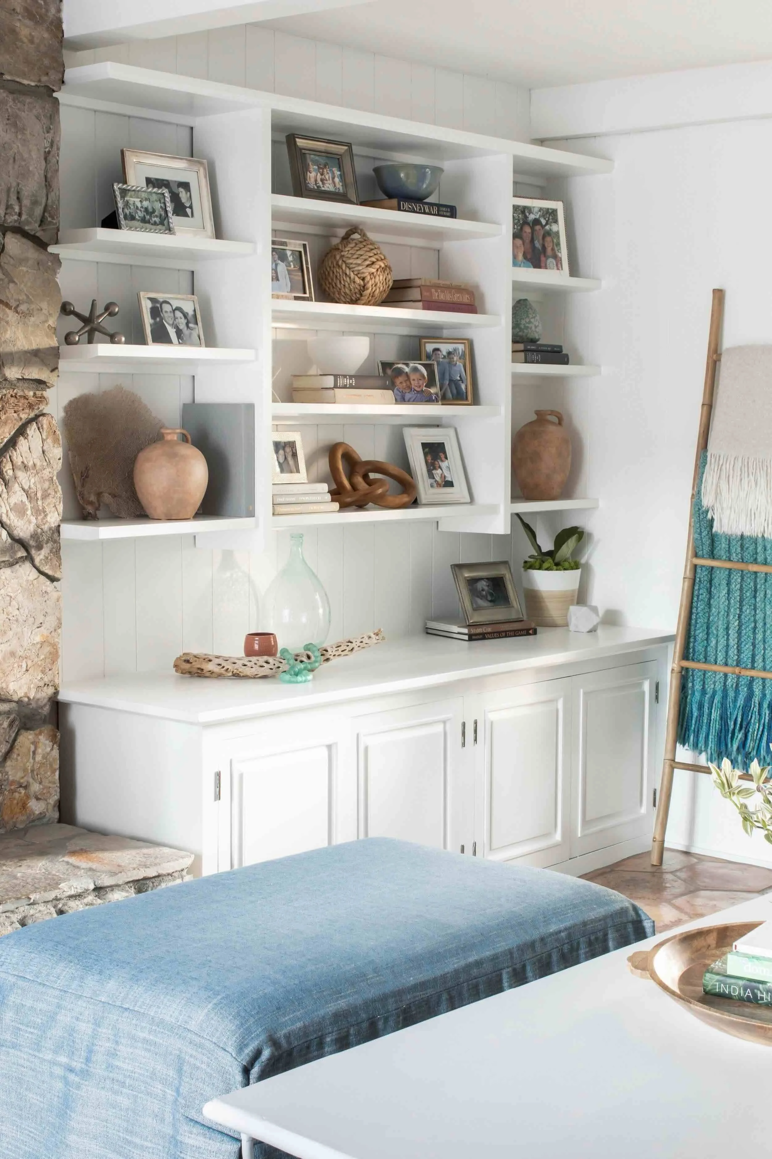 White built-in shelving styled with family photos, books, pottery, and natural textures in Palos Verdes Estates by JKB Home Design