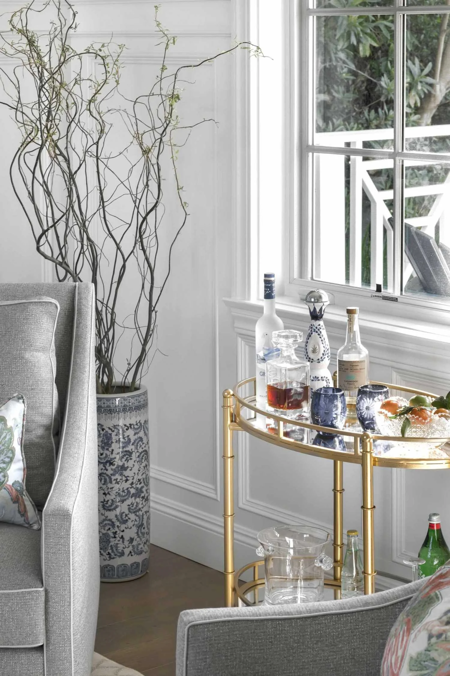 Brass bar cart with glassware and botanicals in parlor, designed by Julie Beuerlein, interior designer