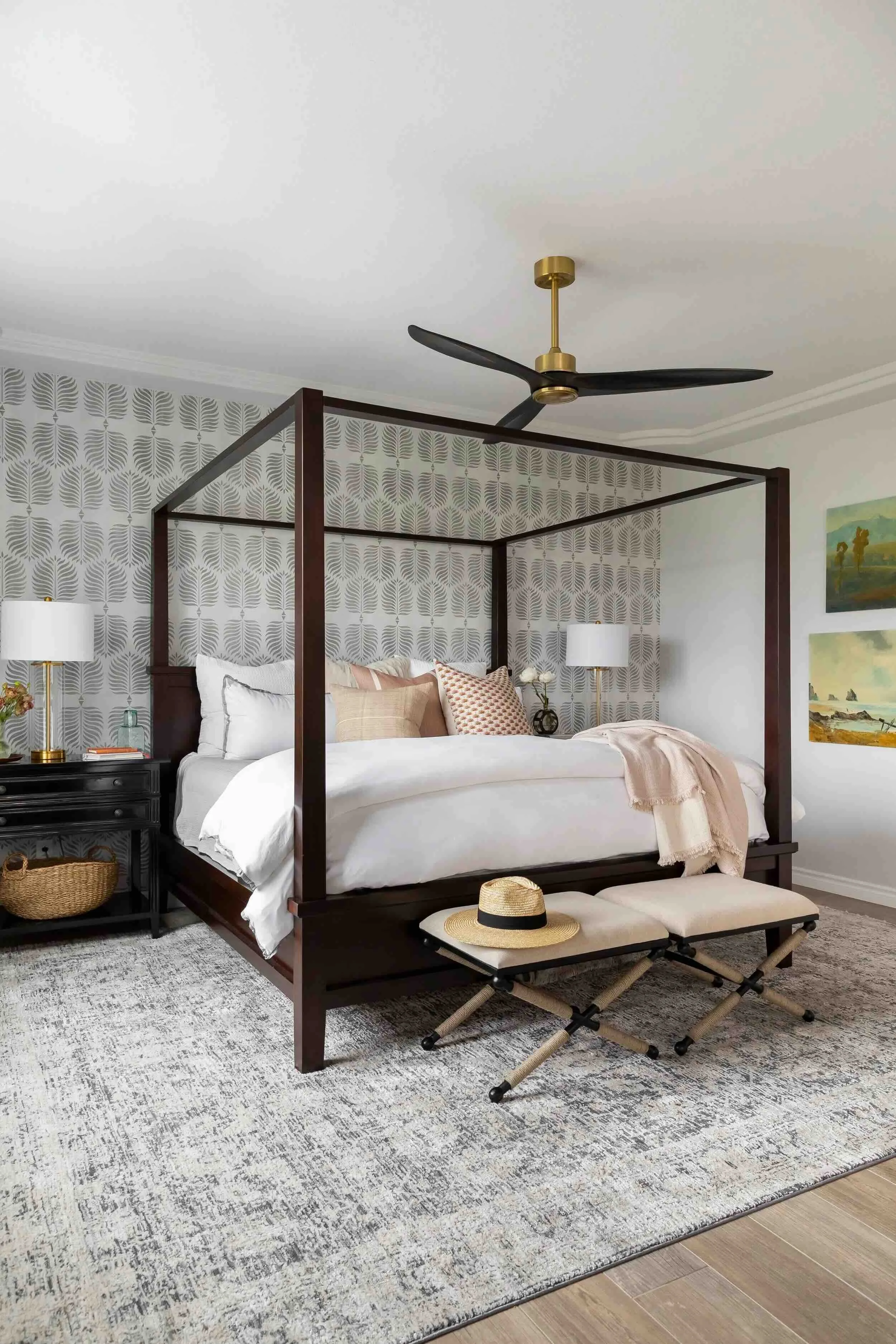 Bedroom with dark wood canopy bed, patterned wallpaper, and layered neutral textiles, designed by Julie Beuerlein