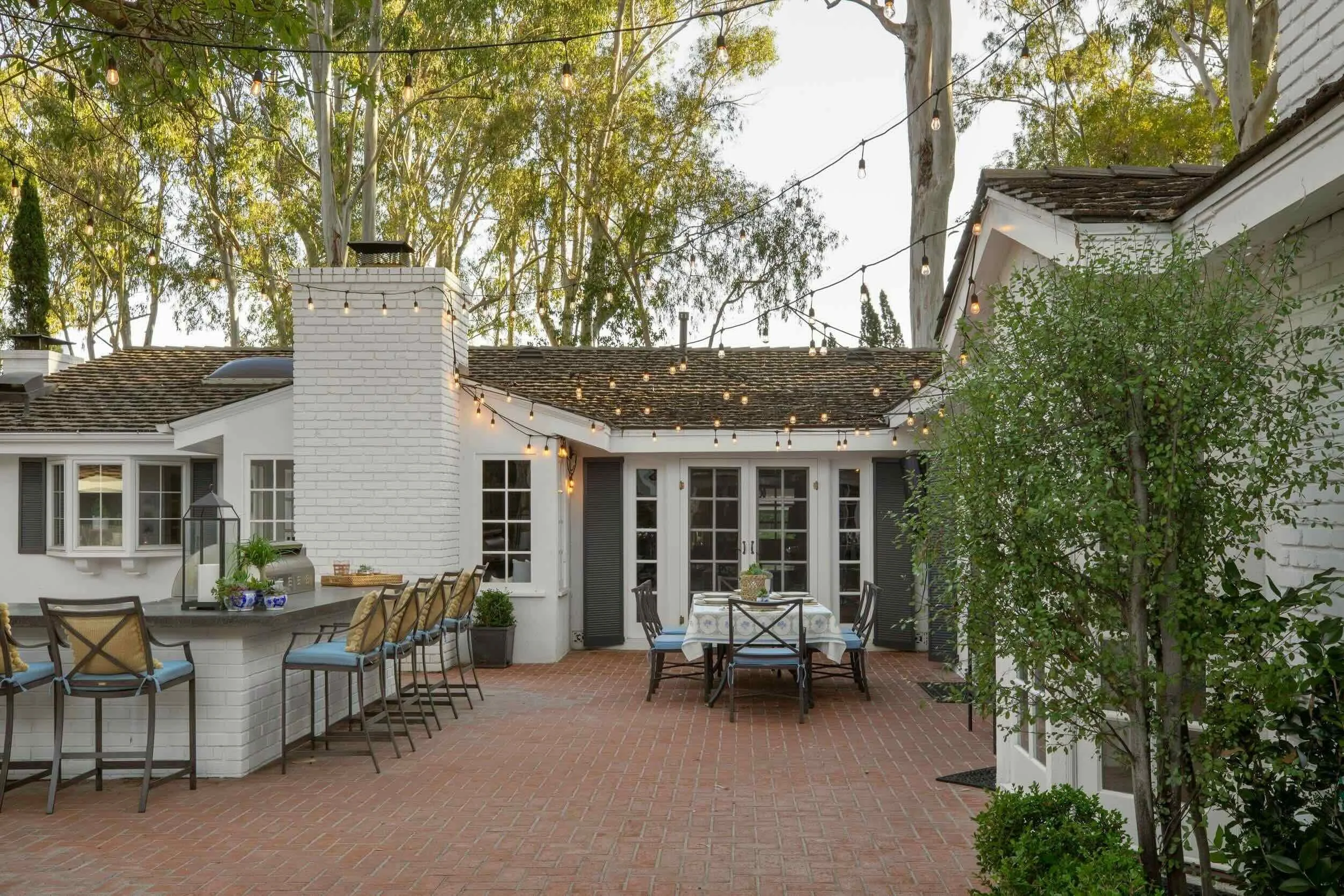 Southern California outdoor kitchen and dining area with brick patio and string lights, designed by JKB Home Design