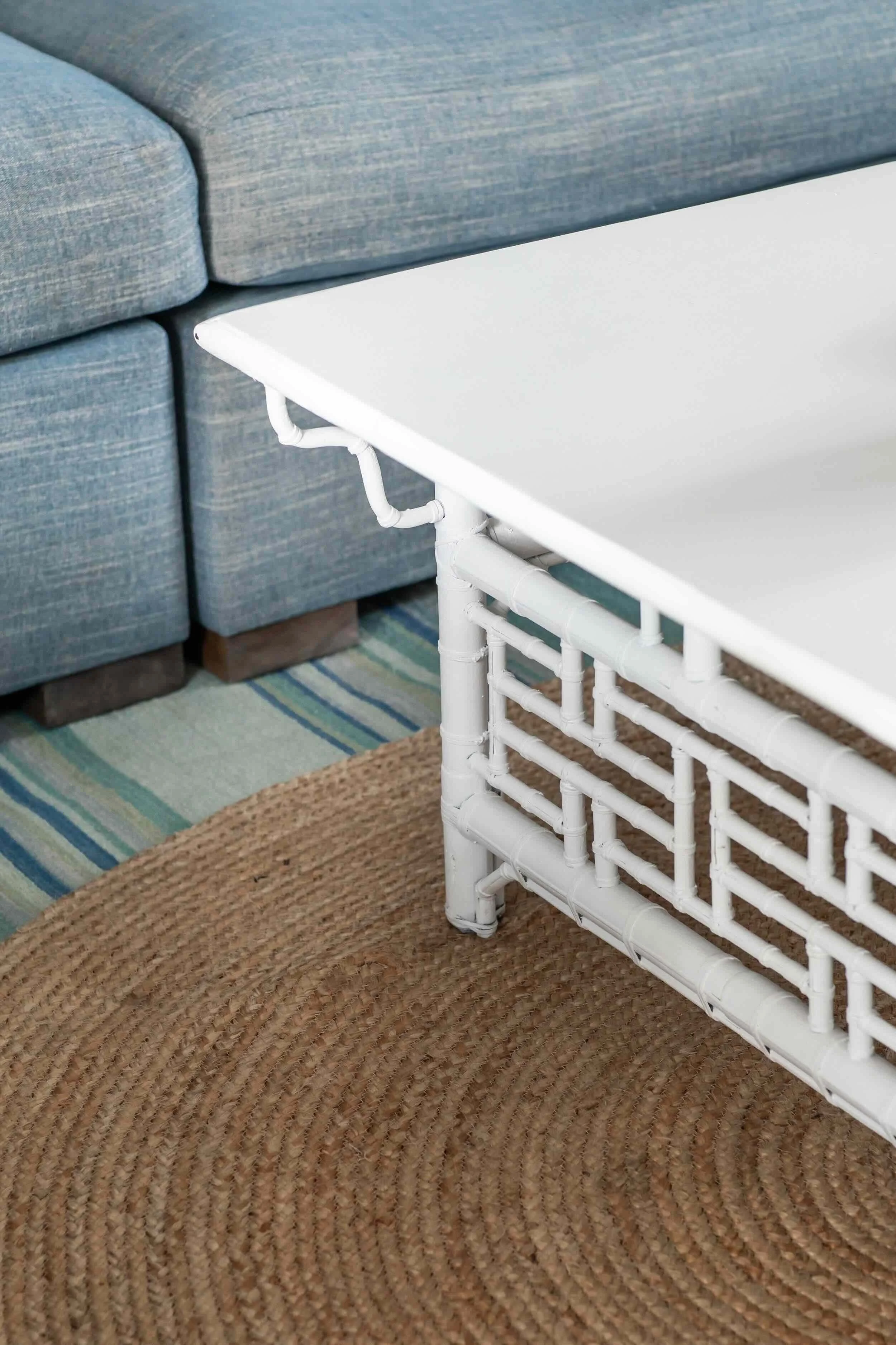 Living room detail with blue sofa, white bamboo-style coffee table, and layered natural fiber rugs in Palos Verdes Estates