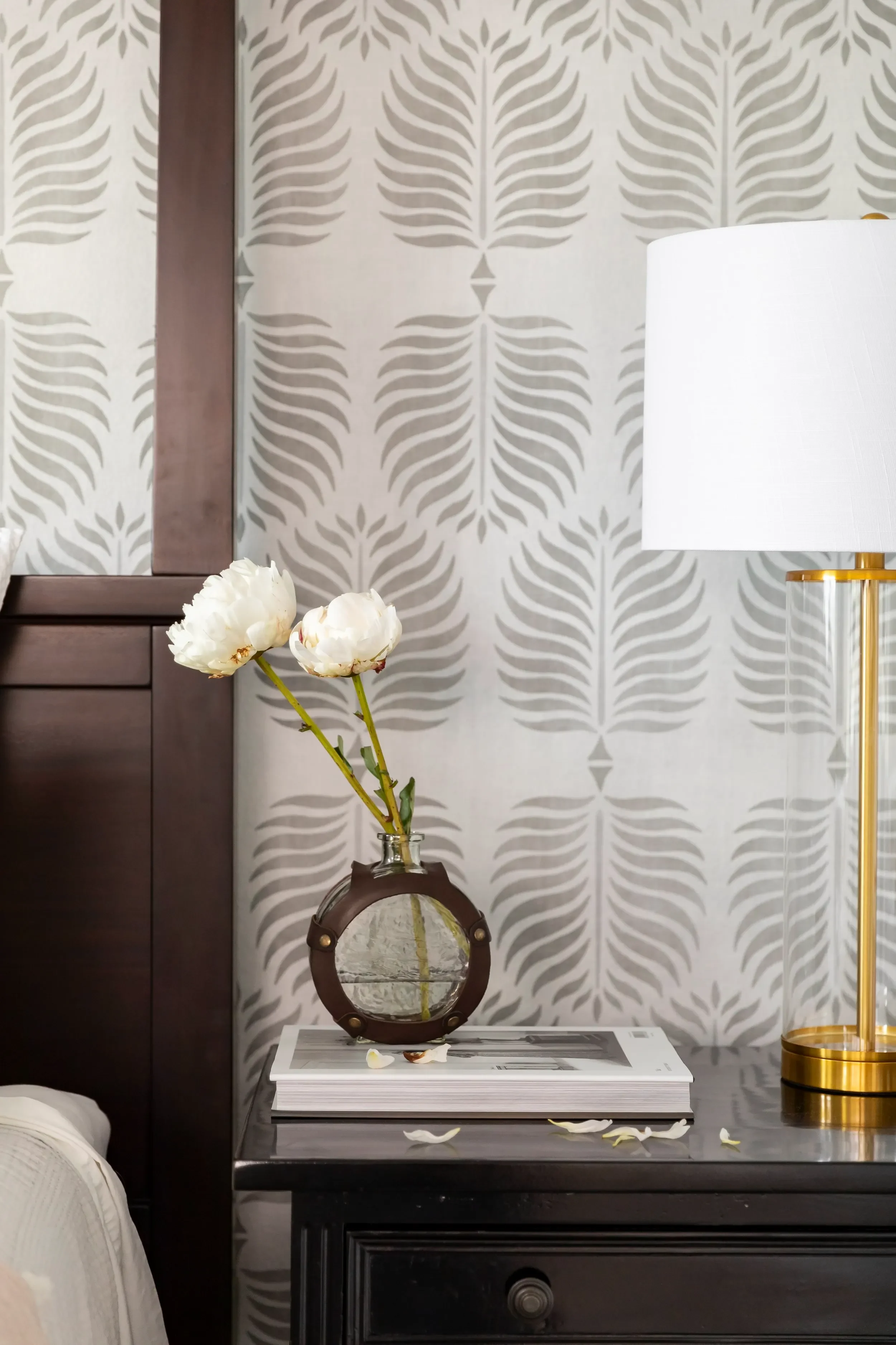 Bedroom detail with botanical wallpaper, dark wood nightstand, and layered accessories in southern California, designed by JKB Home Design