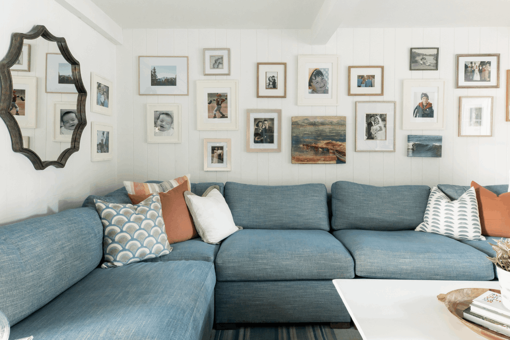 Family photo gallery wall above a custom blue sectional in a Palos Verdes Estates home designed by Julie Beuerlein